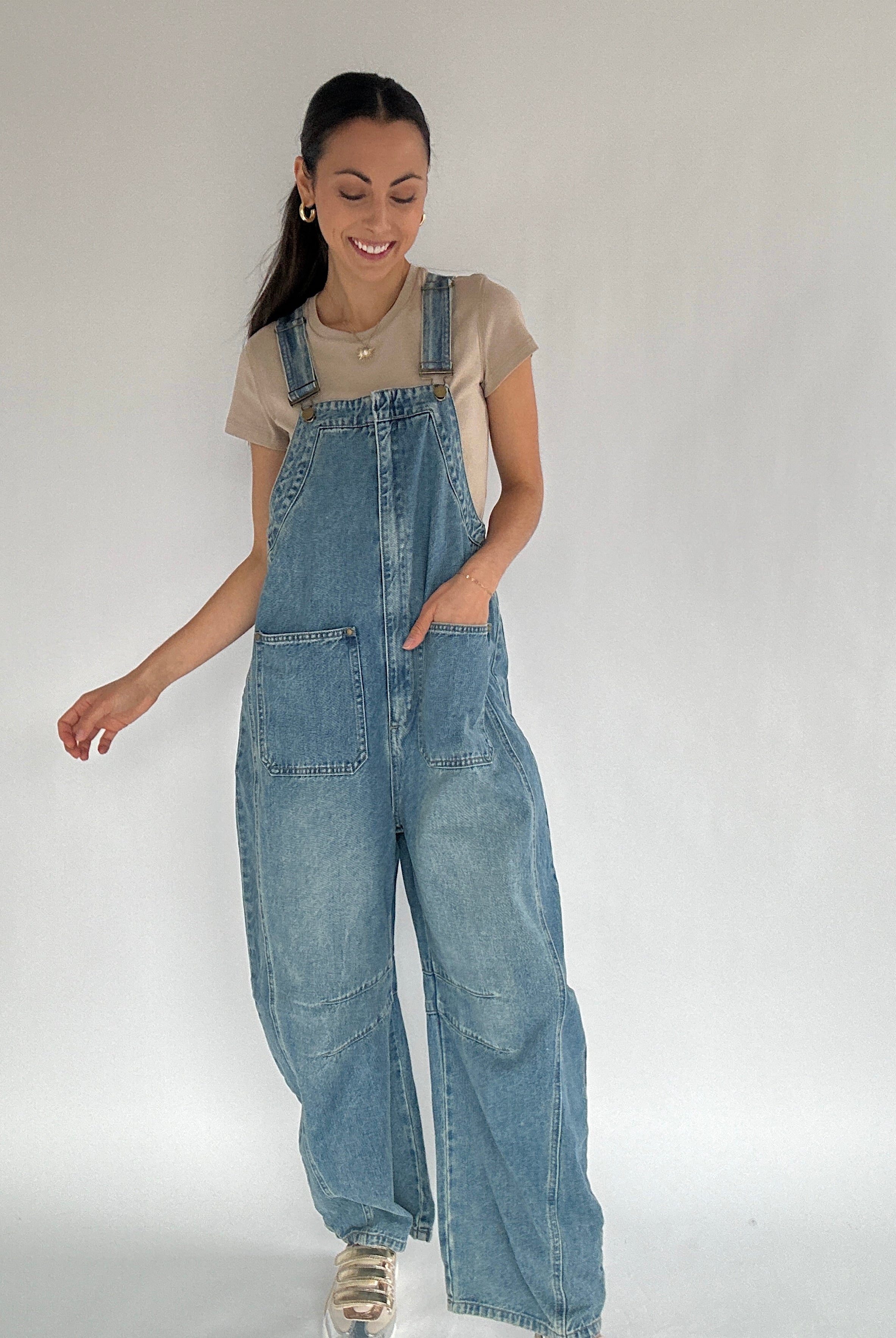 Woman wearing blue denim overalls on a plain background