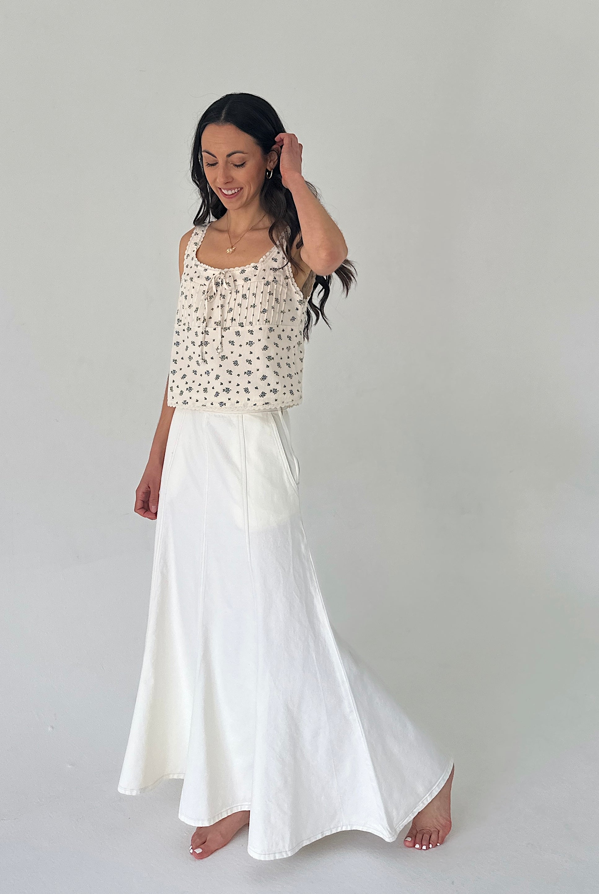 Woman wearing a patterned top and white skirt on a plain background