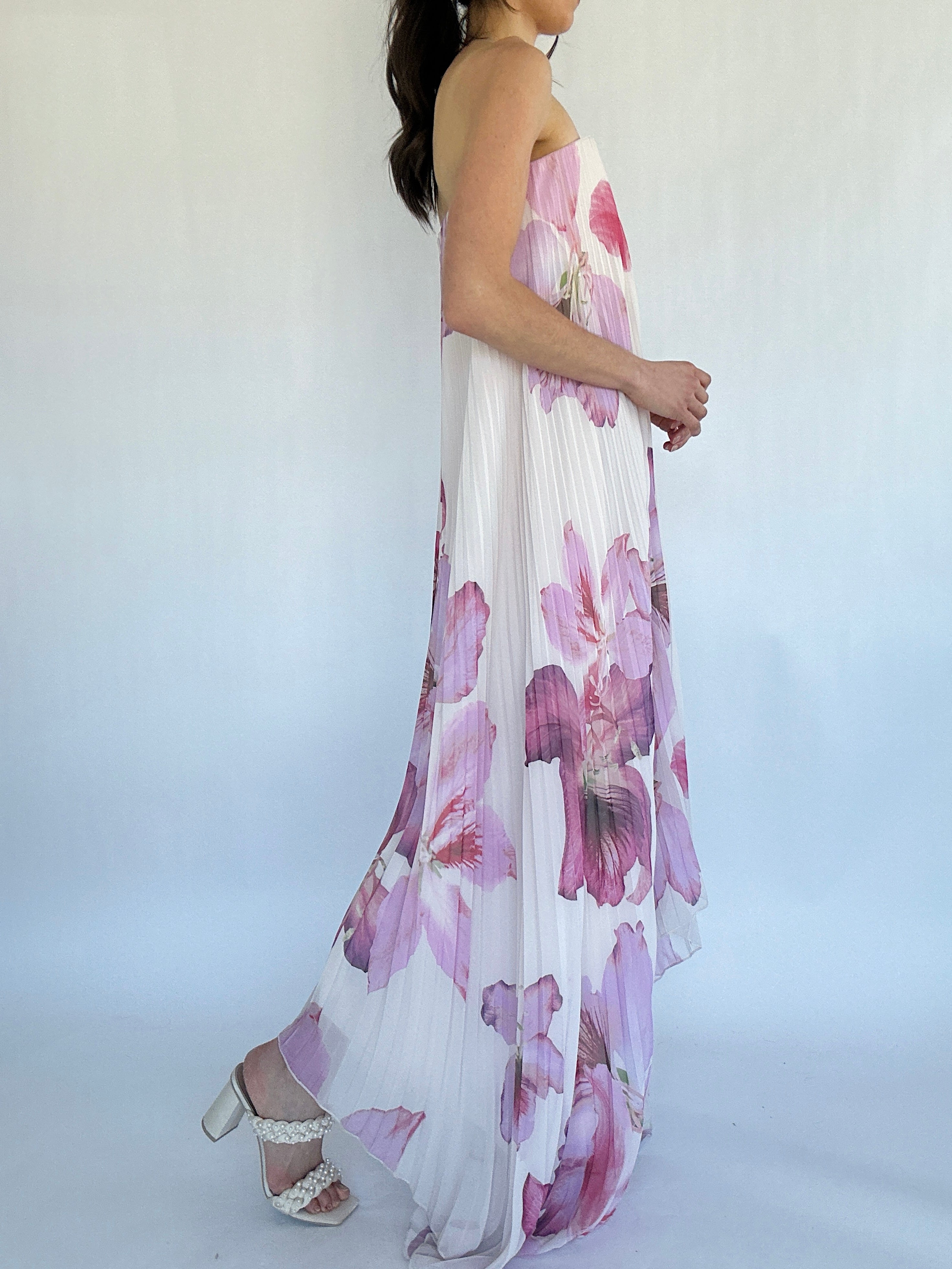 Woman wearing a floral dress with a white background from side