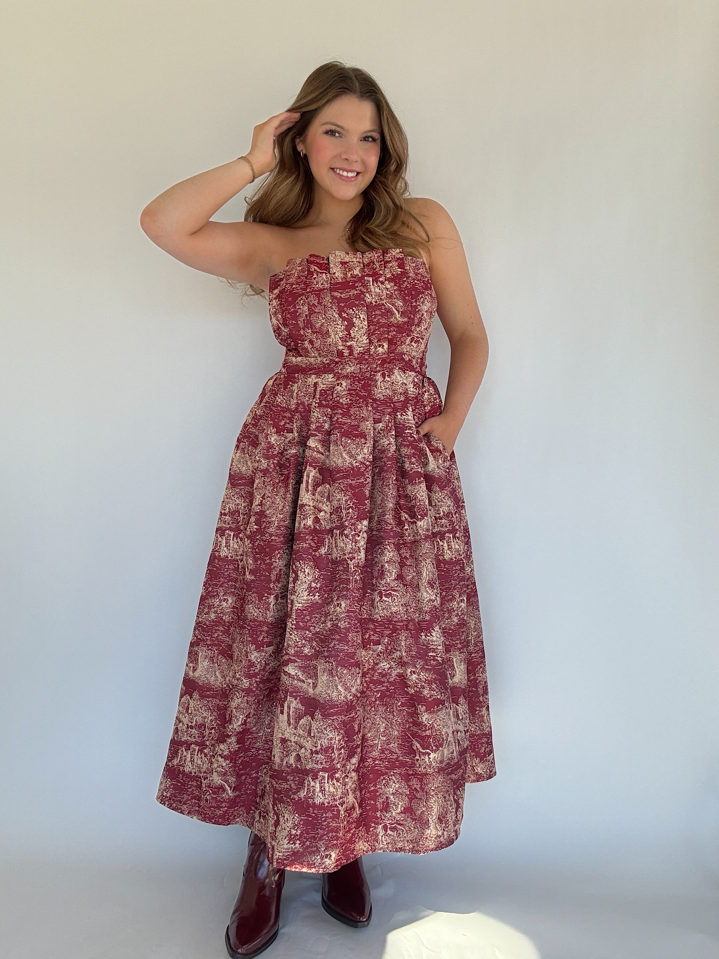 Woman wearing a red toile floral dress against a white background