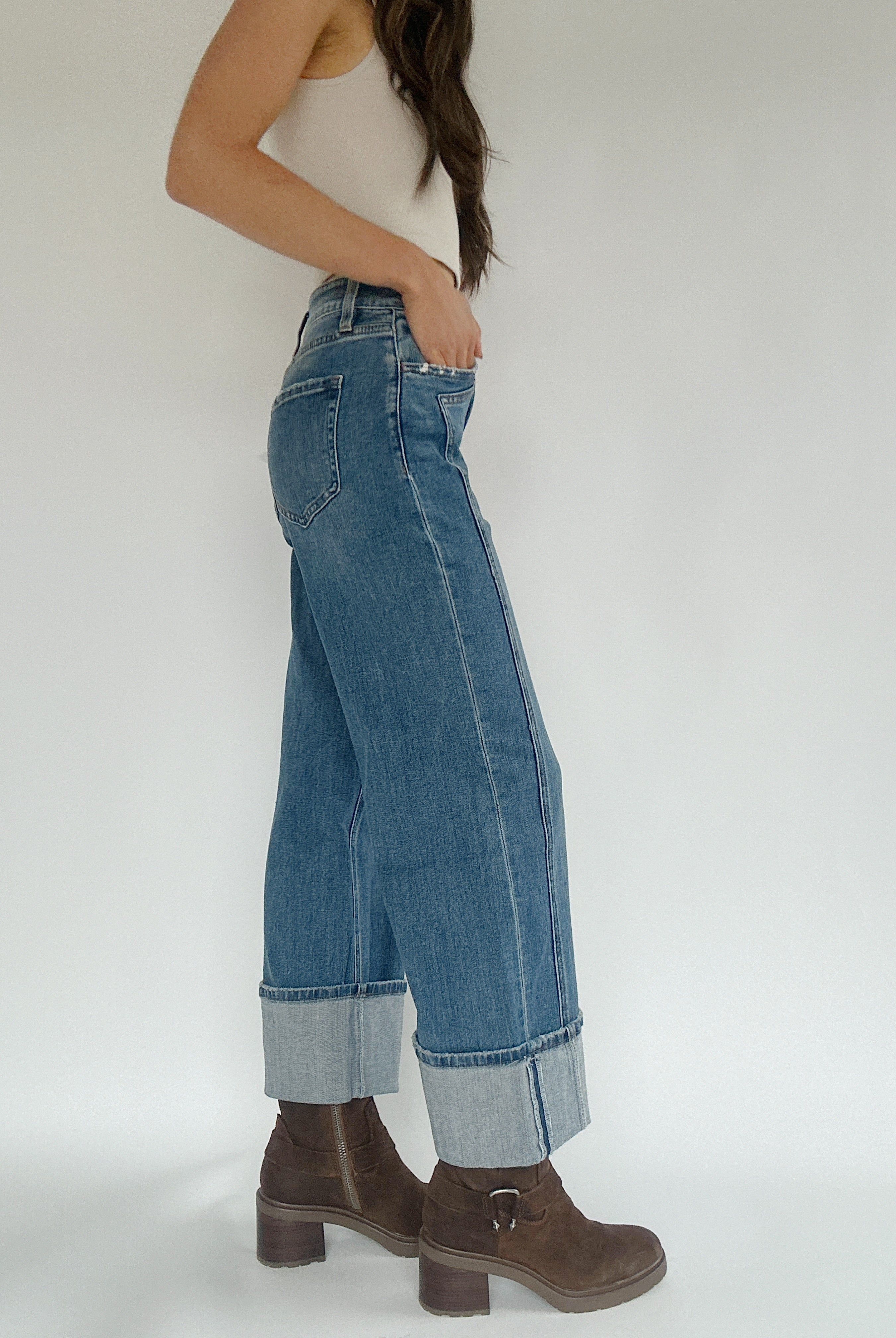 Woman wearing medium wash wide leg jeans ith a cuffed bottom showing the side.