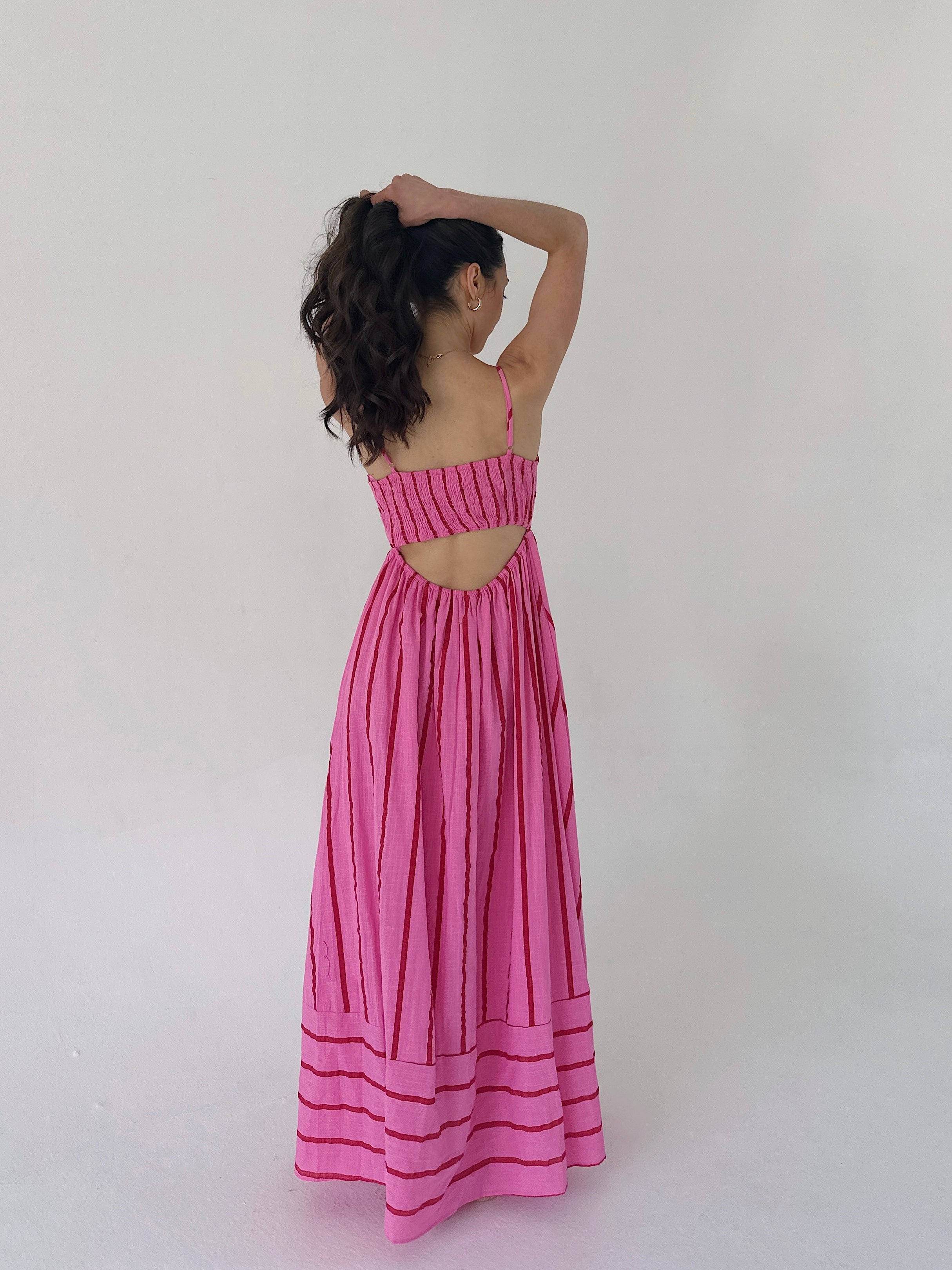Woman wearing a pink dress with back cut-out back on a white background