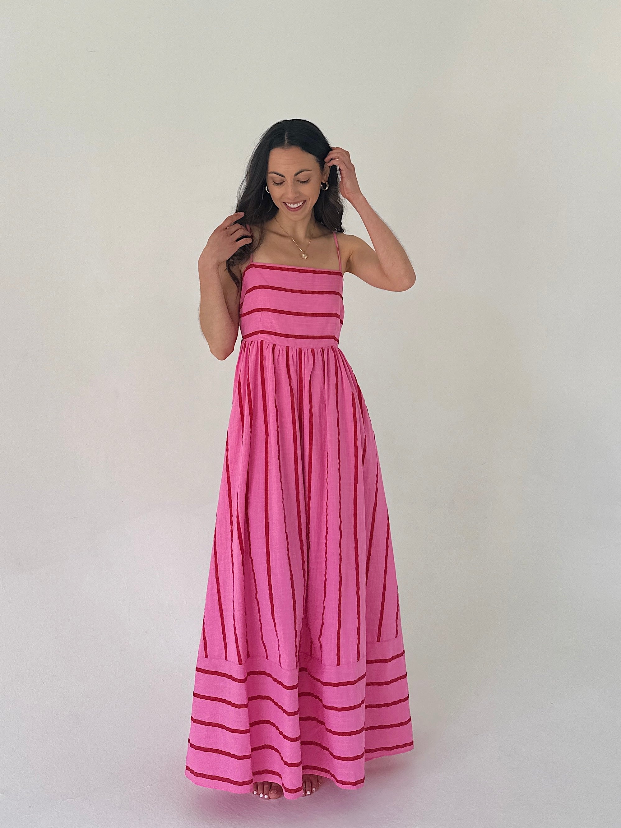 Woman wearing a pink dress with horizontal stripes on a white background