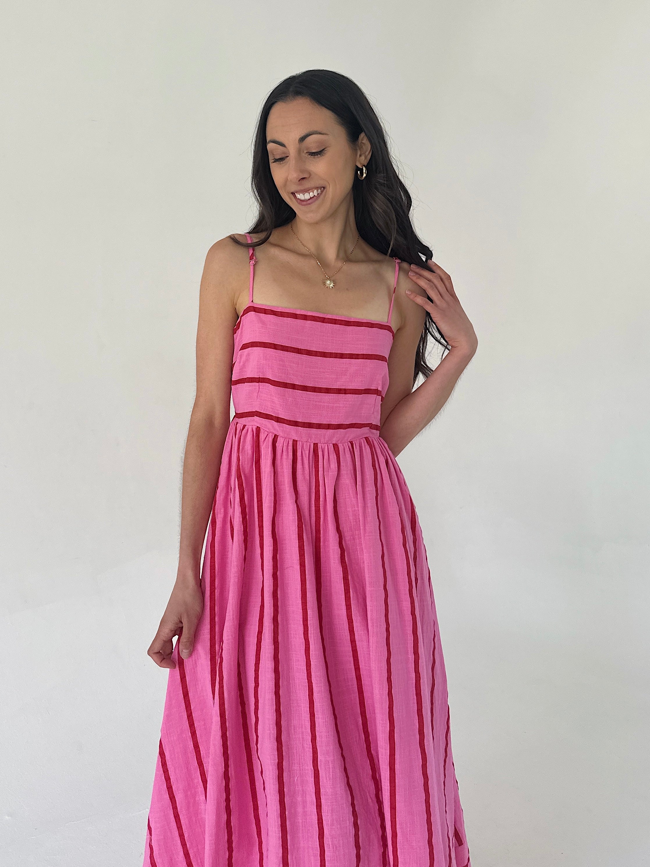 Woman wearing a pink dress with red stripes against a white background