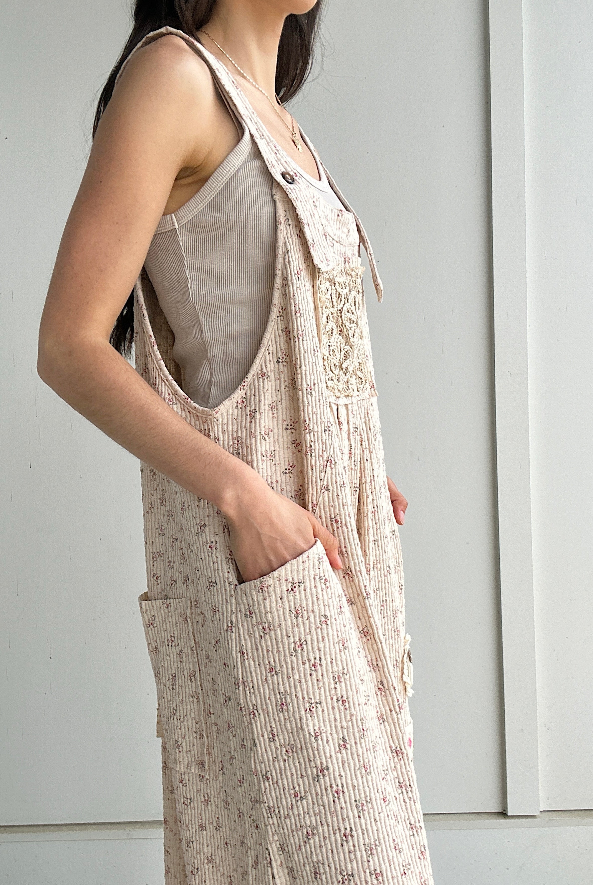 Person wearing a beige overalls with a plain background showing side pockets