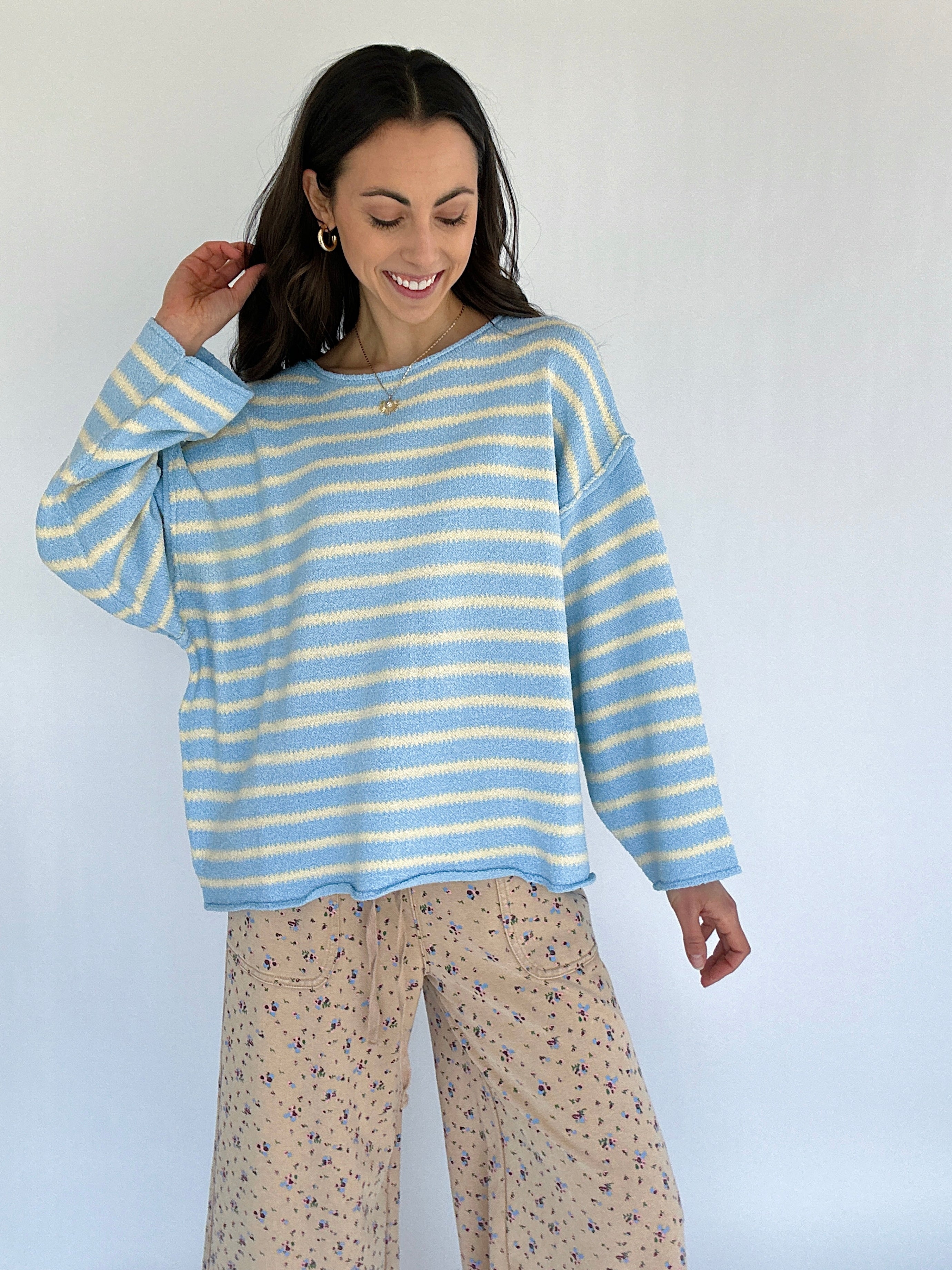 Woman wearing a blue and white striped sweater with patterned pants against a white background