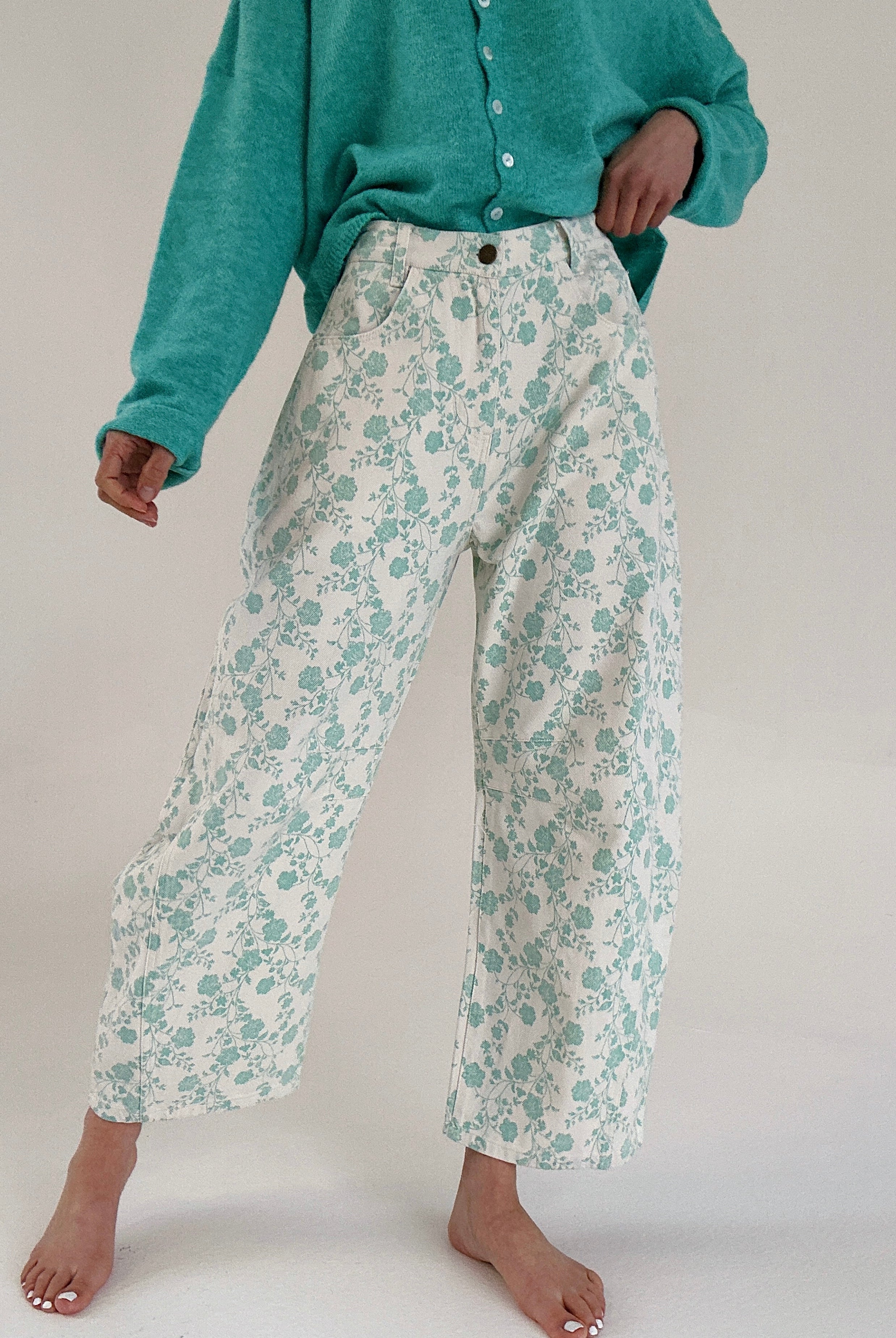 Person wearing teal floral pants and a matching cardigan on a white background