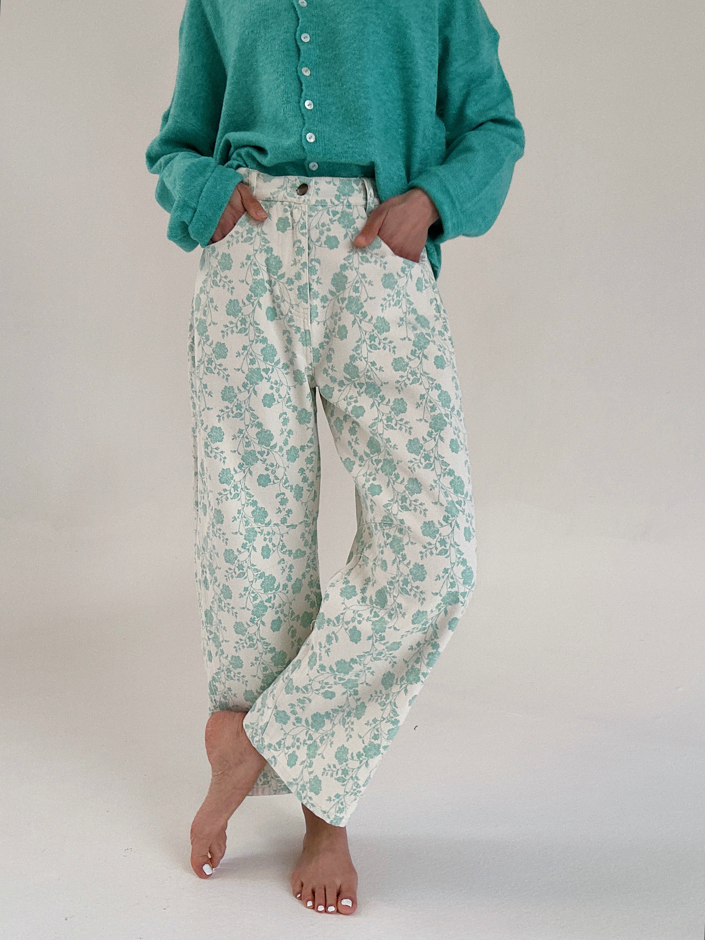 Person wearing teal floral pants and a matching top on a plain background