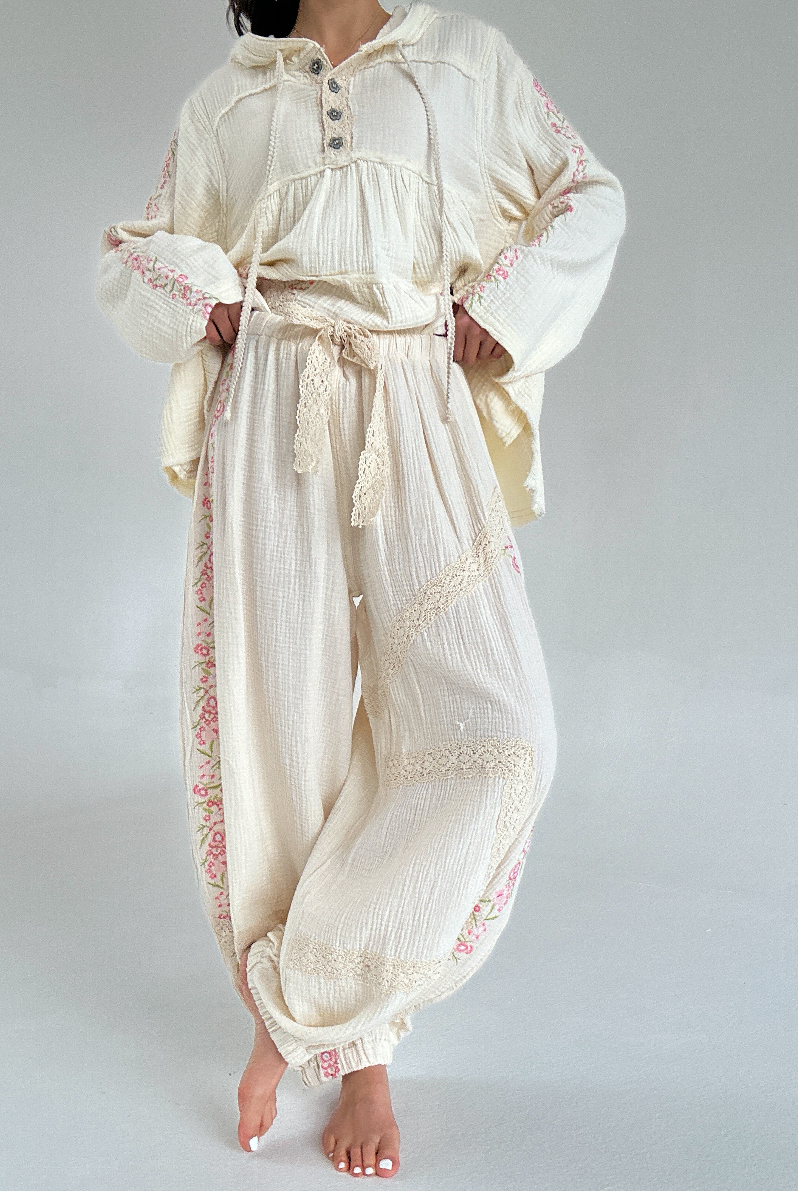 Person wearing a cream-colored outfit with lace details on a plain background