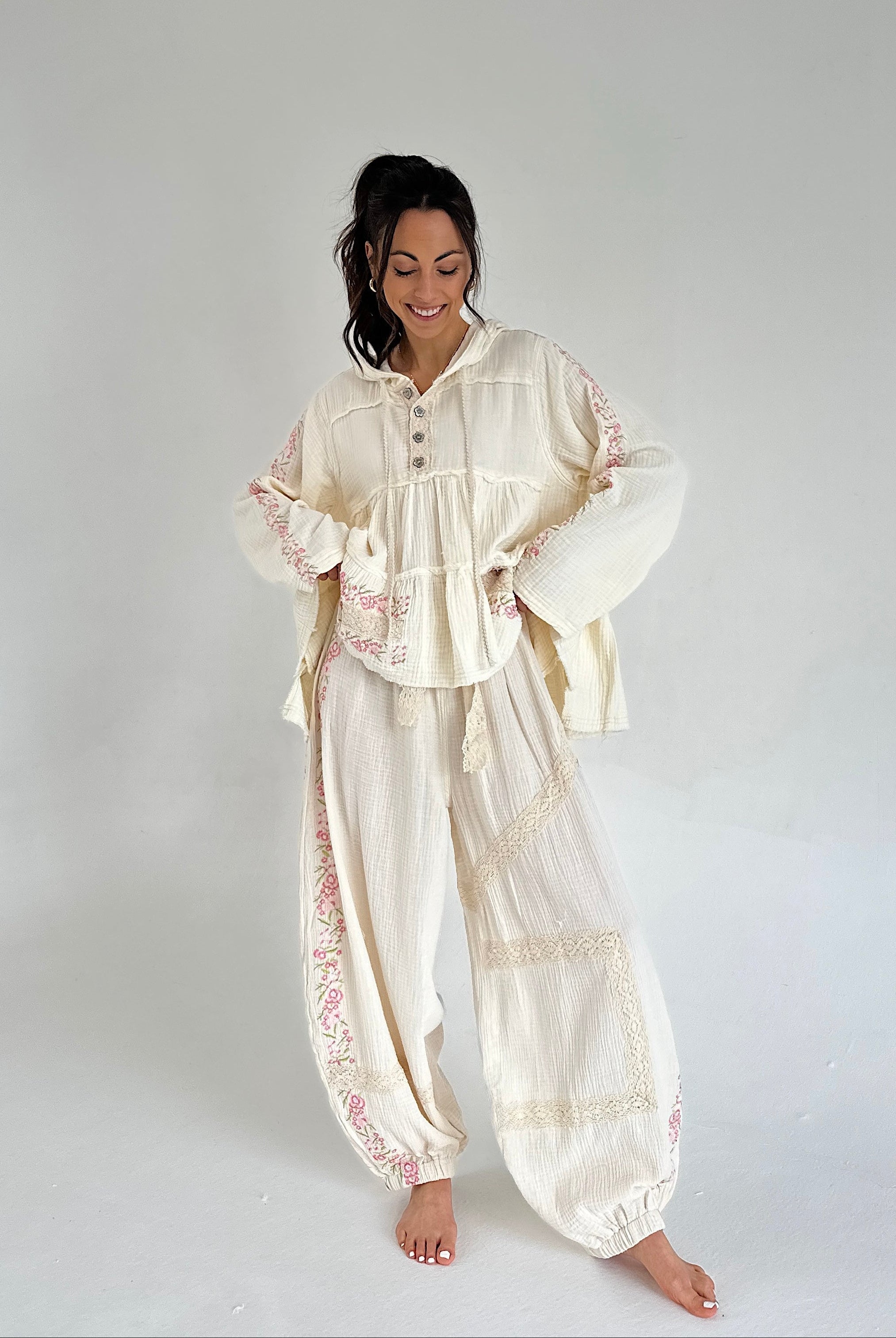 Woman wearing a cream-colored embroidered outfit on a white background