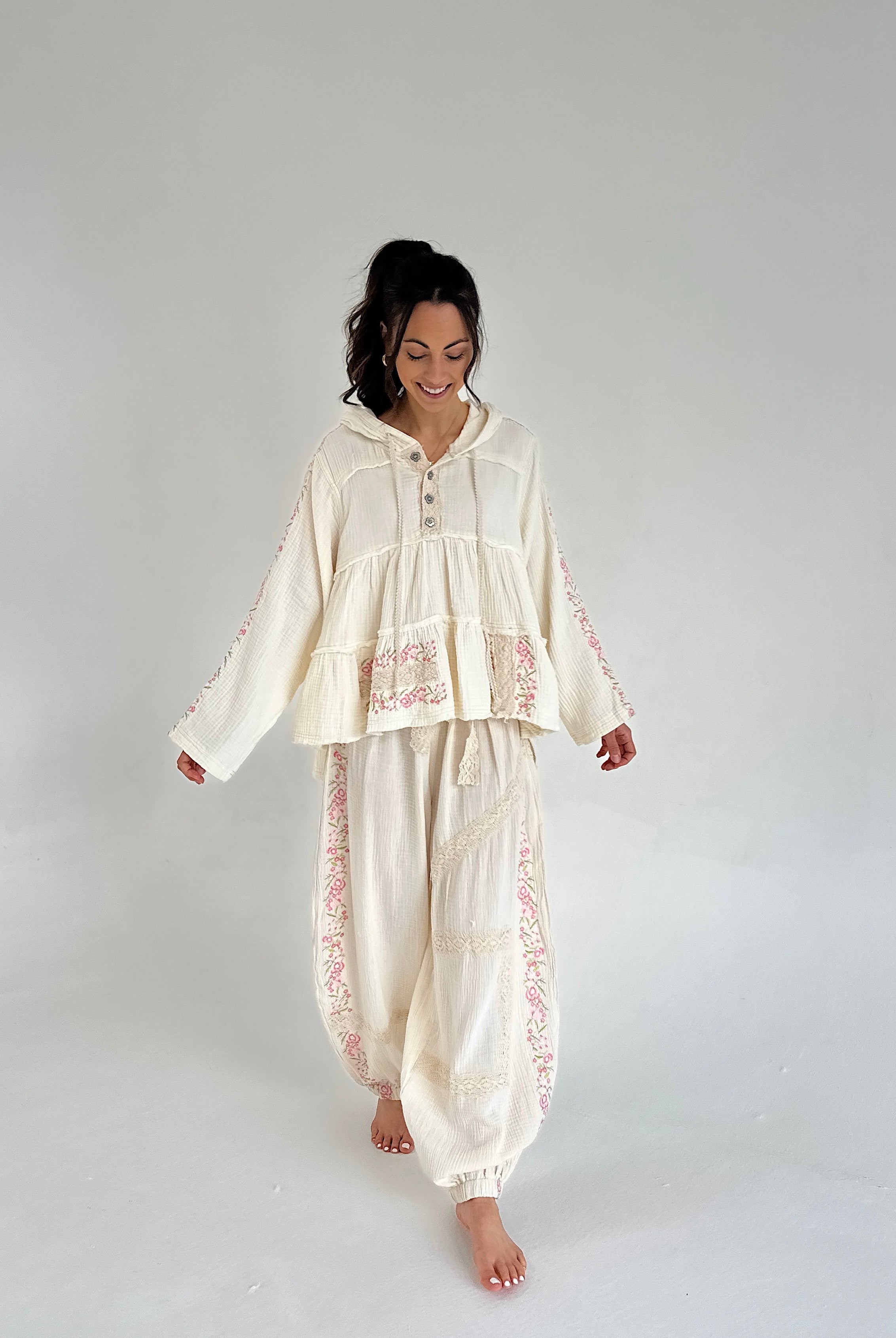 Woman wearing a cream-colored outfit with floral patterns on a plain background