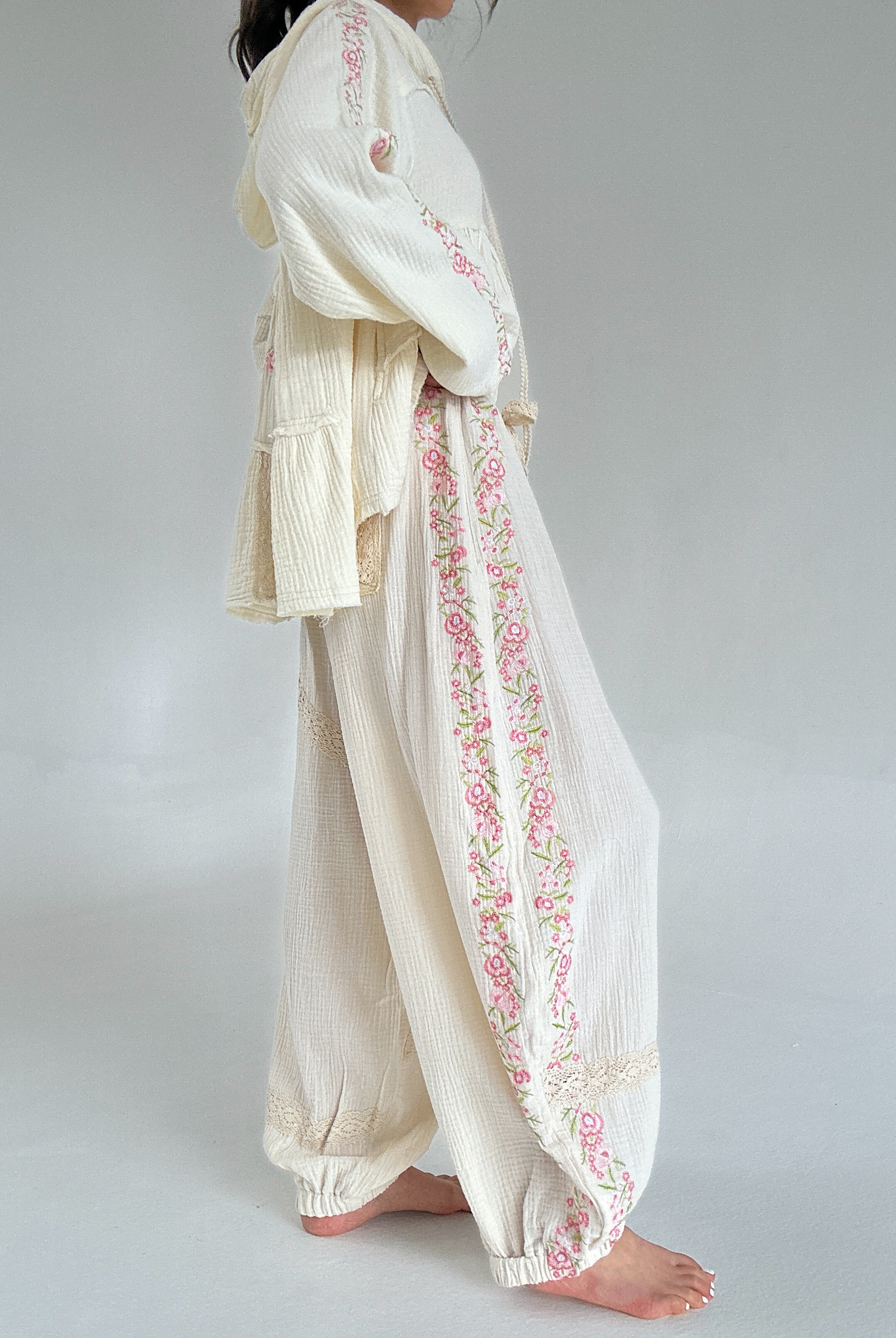 Person wearing a cream-colored outfit with floral embroidery on a plain background showing side embroidery