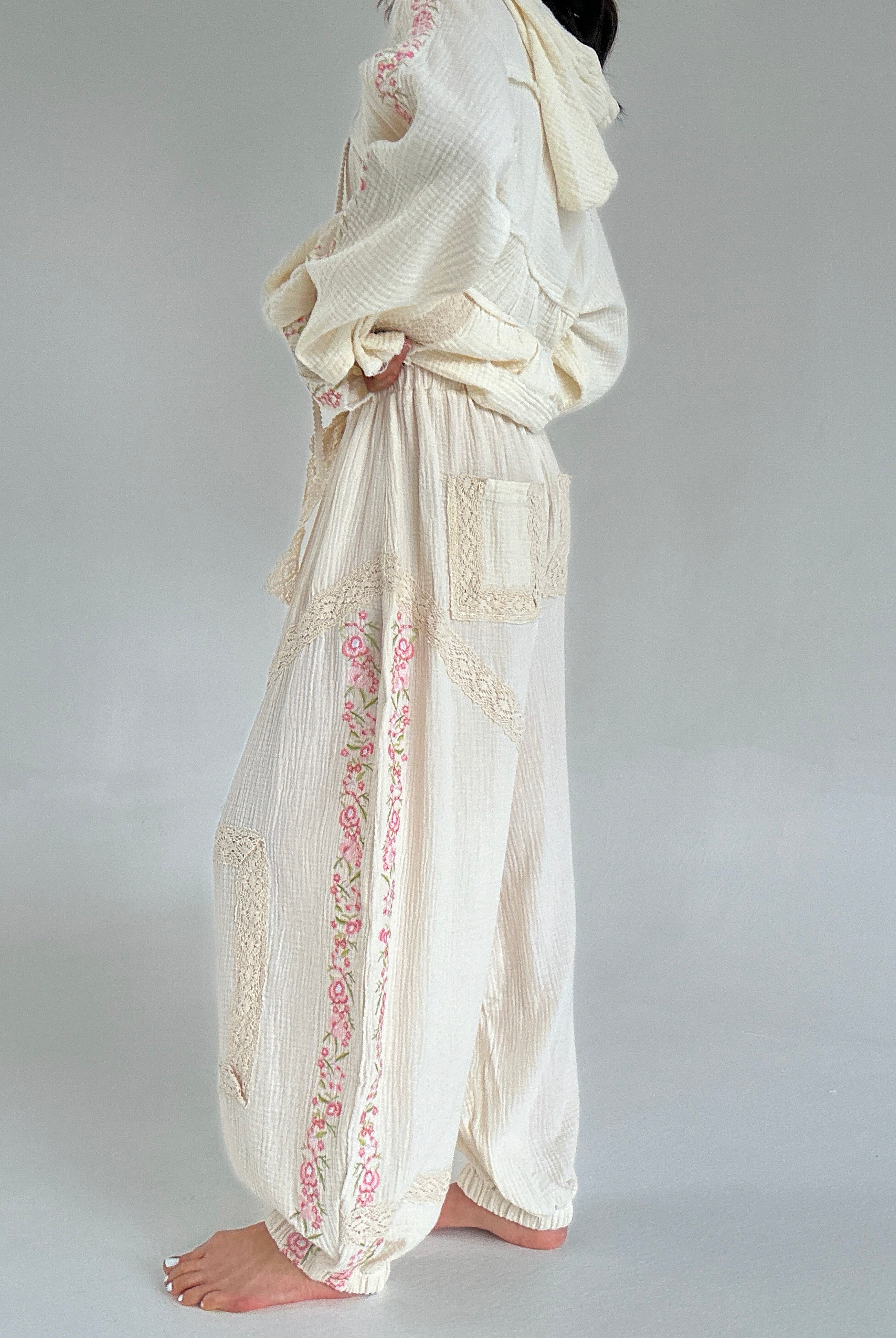 Long, flowing white pants with floral embroidery on a plain background