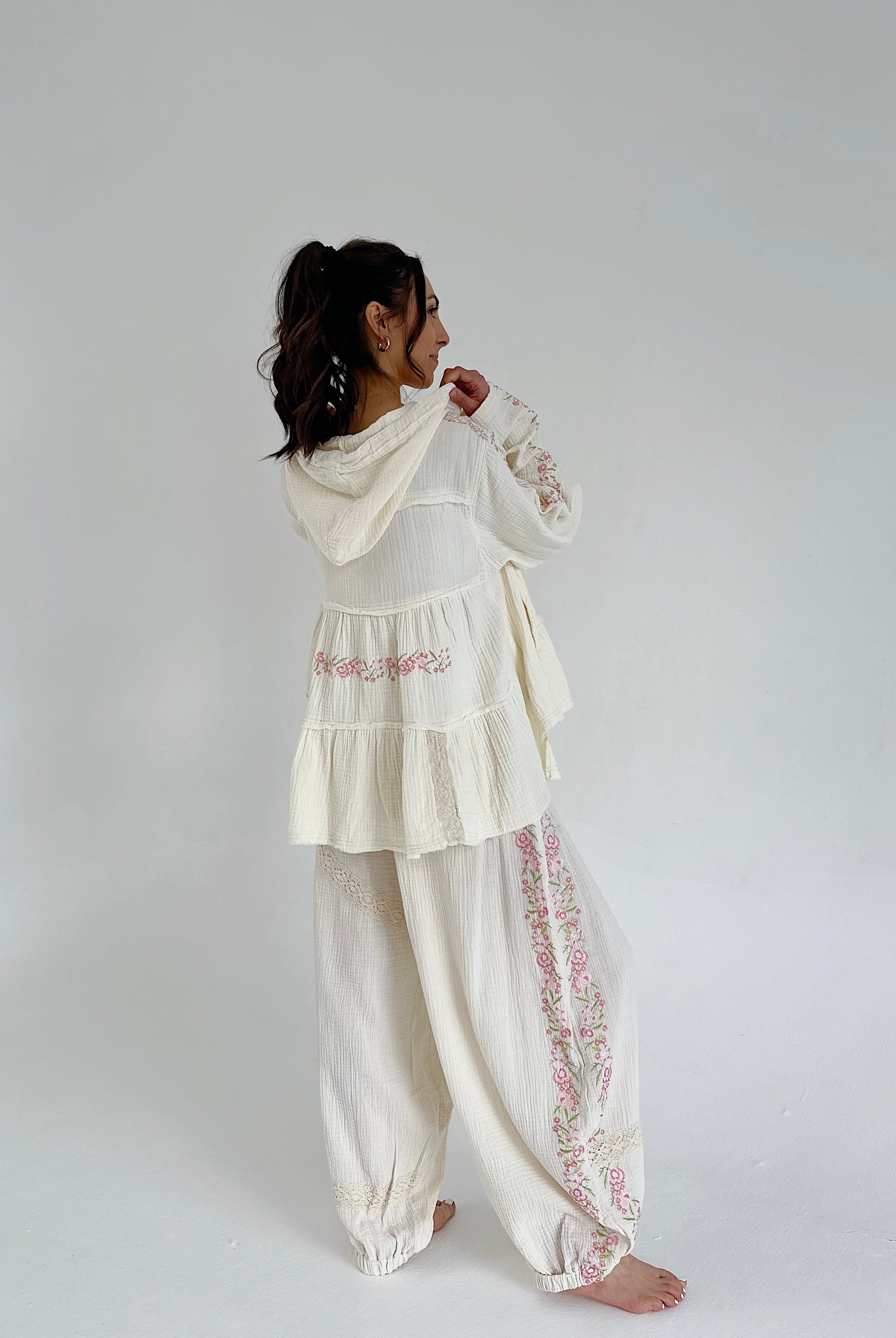 Person wearing a white embroidered outfit on a plain background