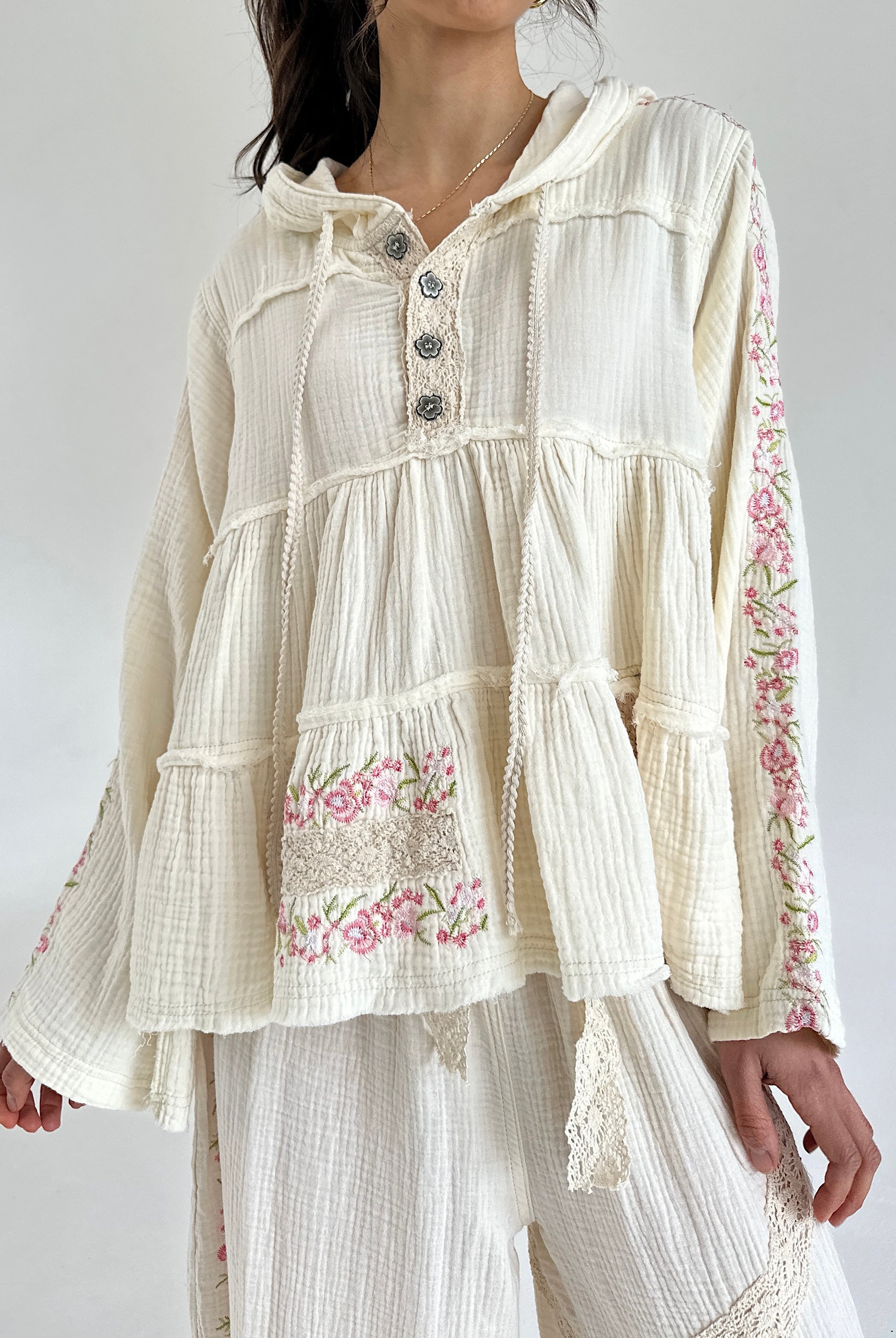 Woman wearing a cream-colored blouse with floral embroidery on a white background