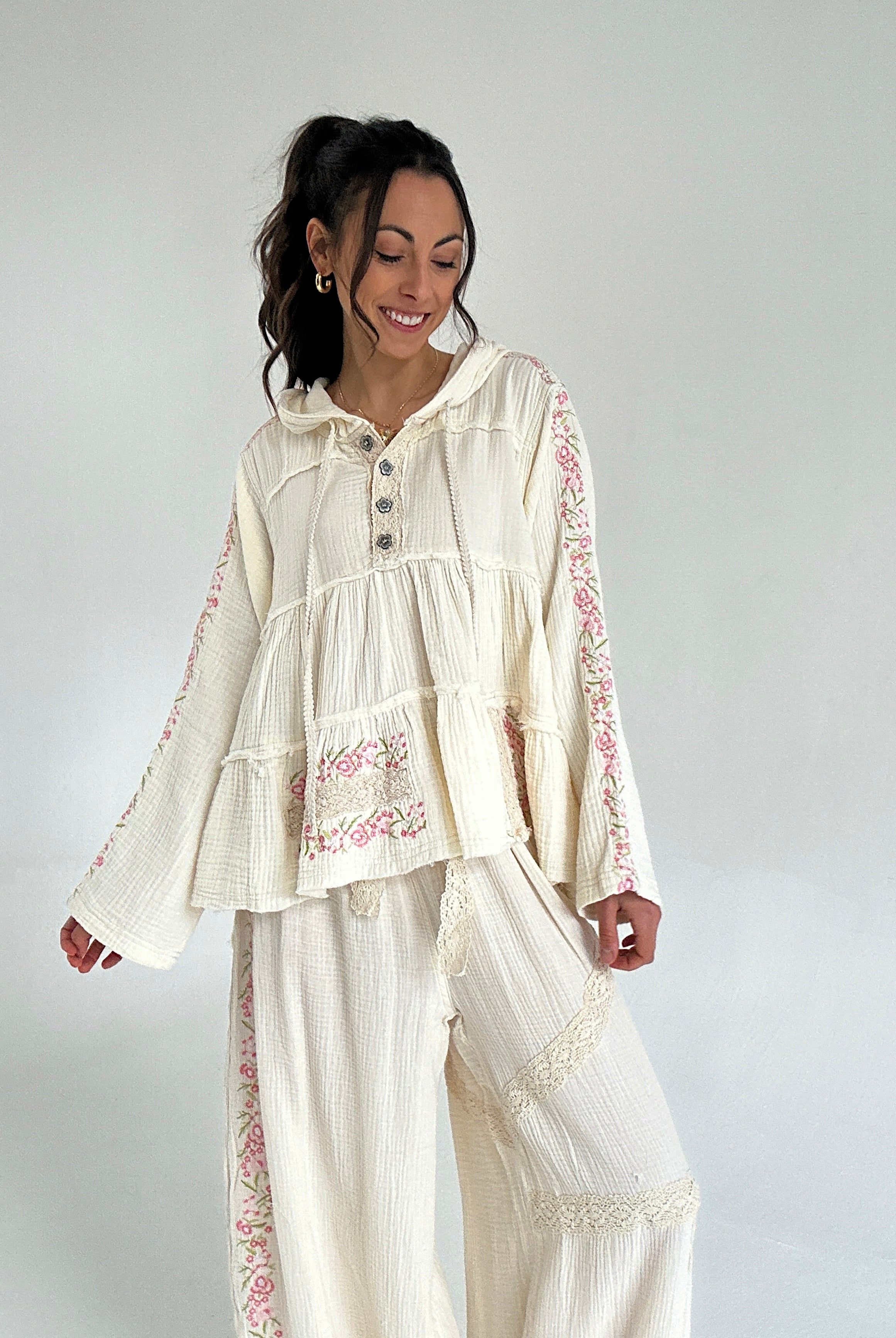 Woman wearing a cream-colored outfit with floral embroidery on a white background