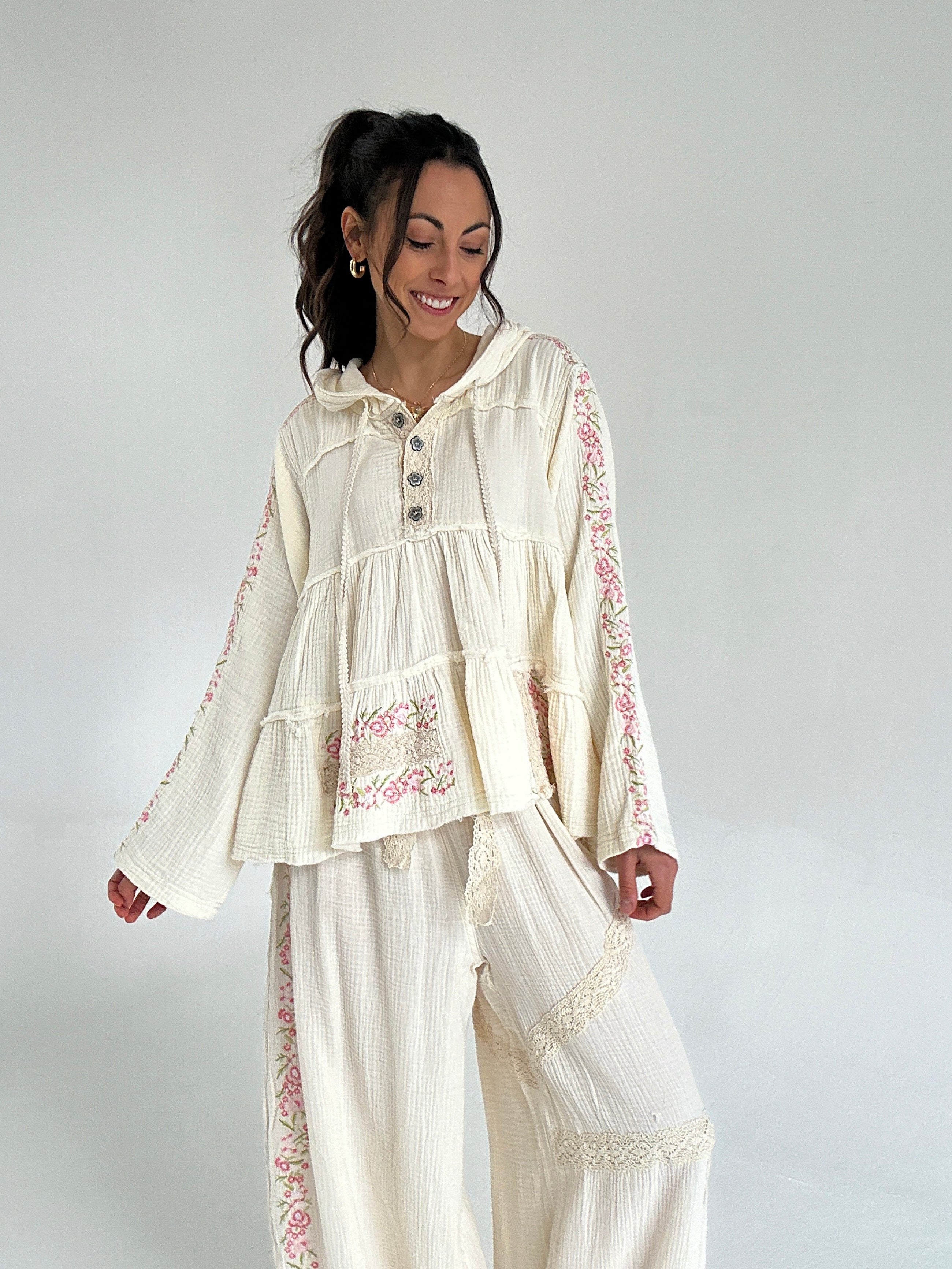 Woman wearing a cream-colored outfit with floral embroidery on a white background