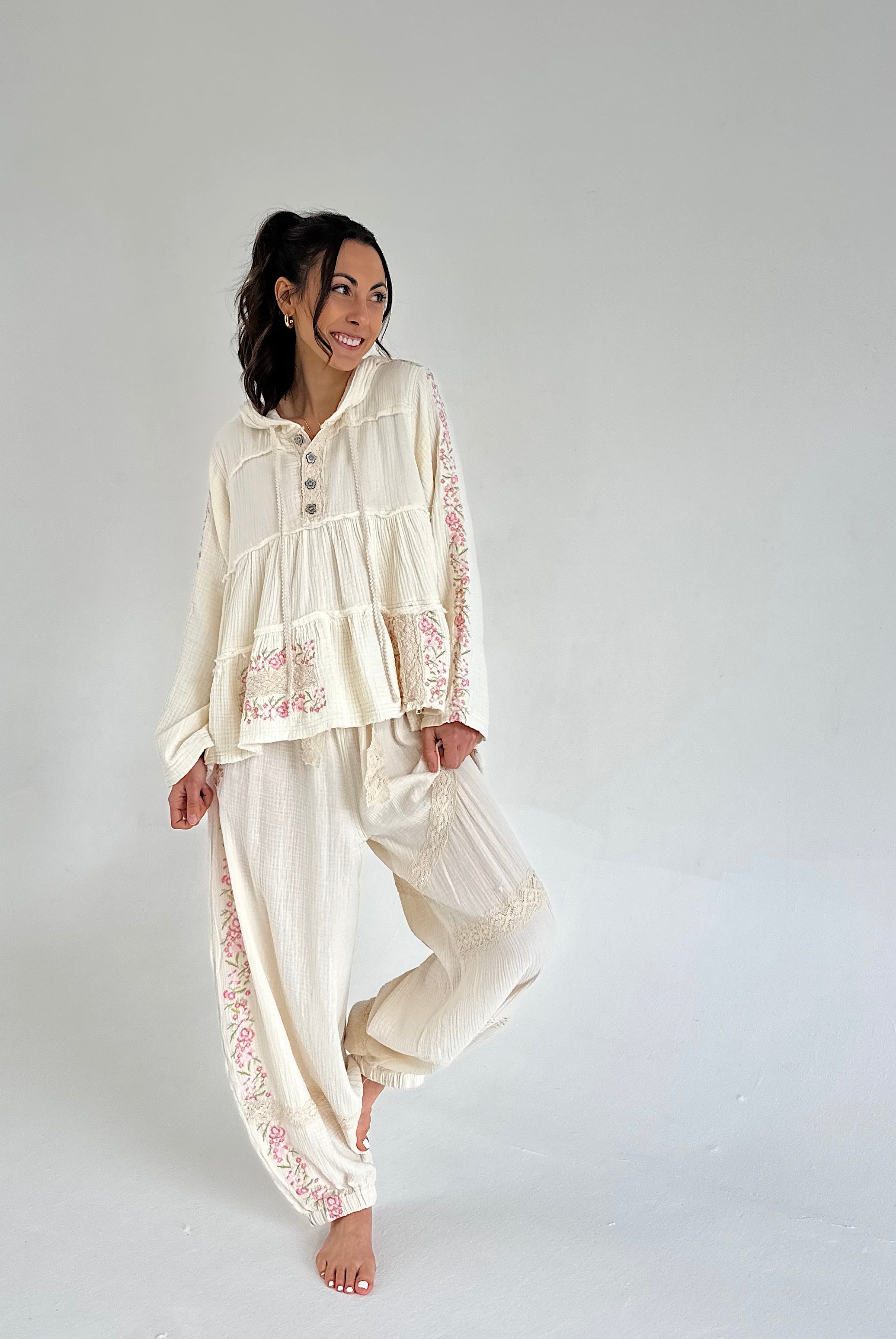 Woman wearing a cream-colored outfit with lace details on a plain background