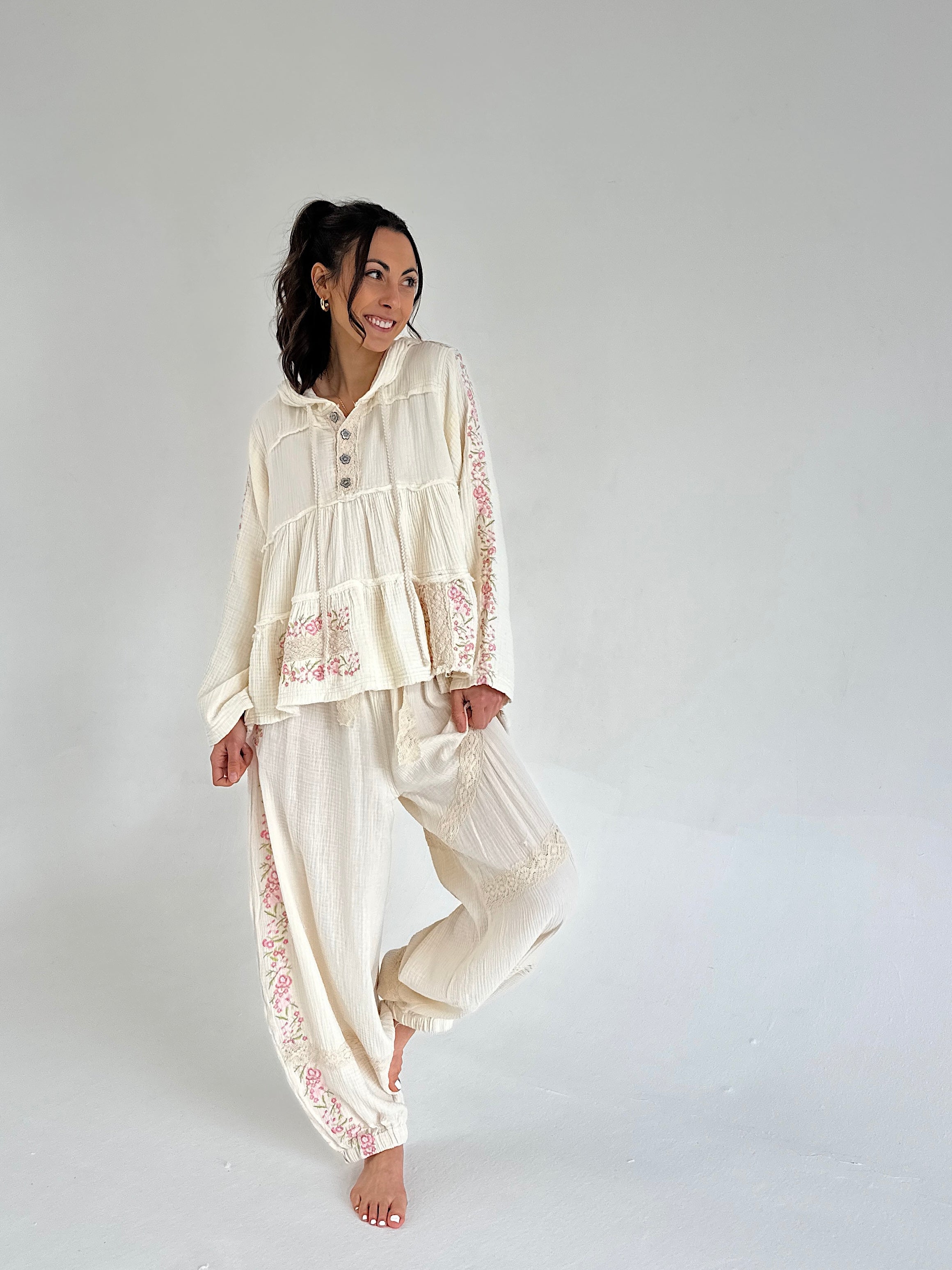 Woman wearing a cream-colored outfit with lace details on a plain background