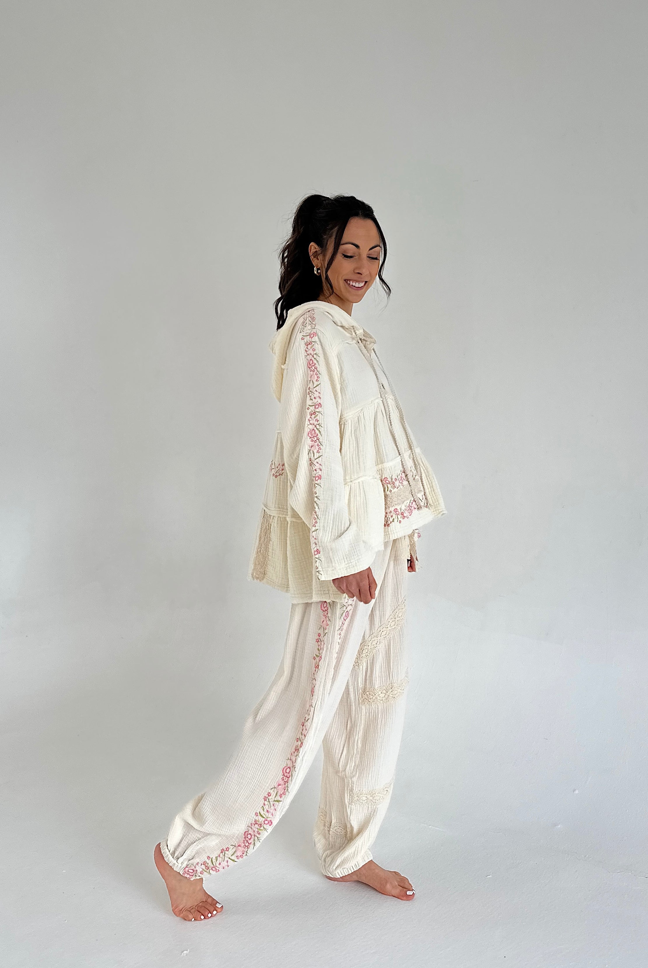 Woman wearing a cream-colored embroidered outfit on a plain background