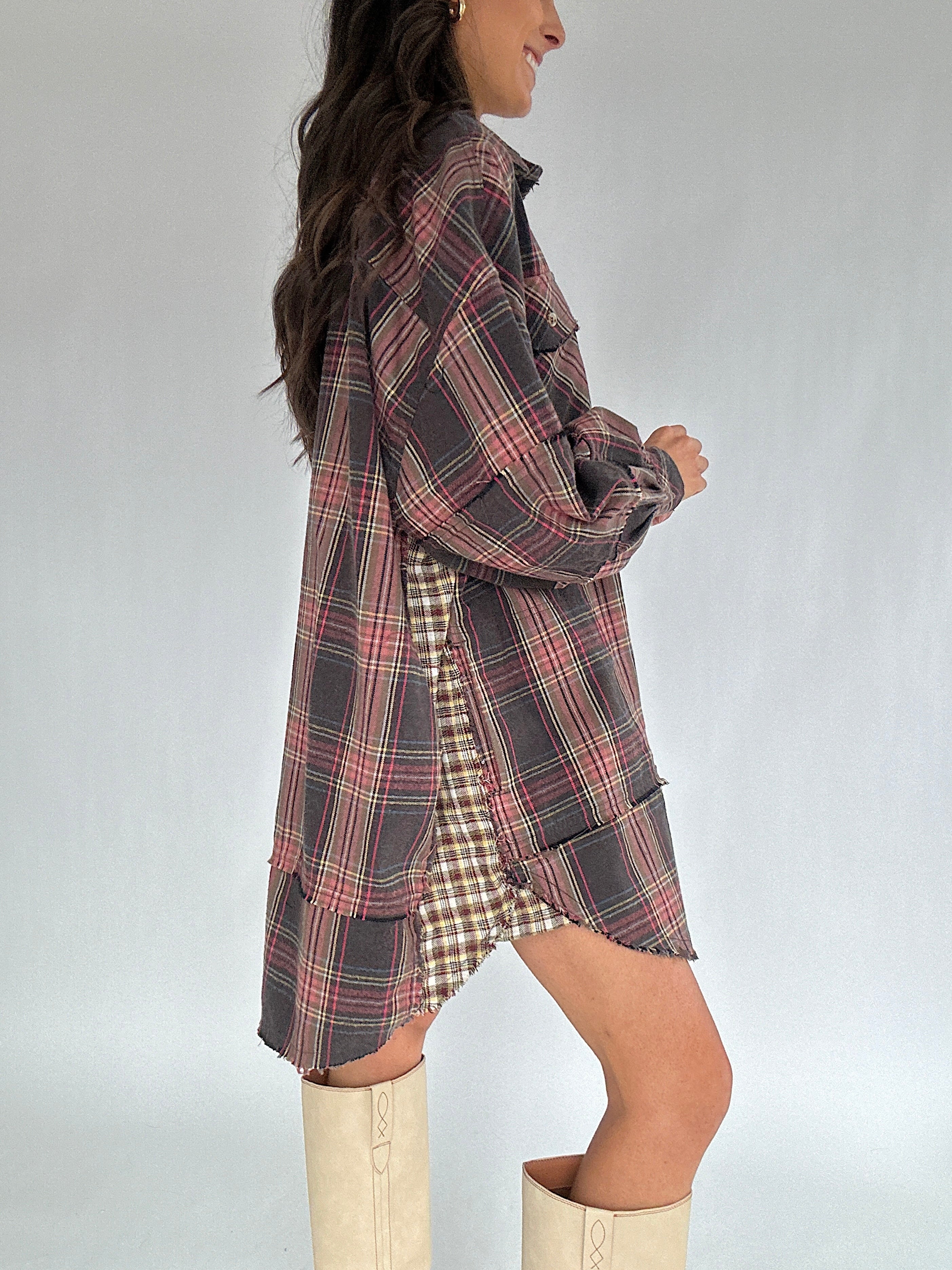 Person wearing a plaid shirt dress with beige boots on a plain background showing contrast side panel