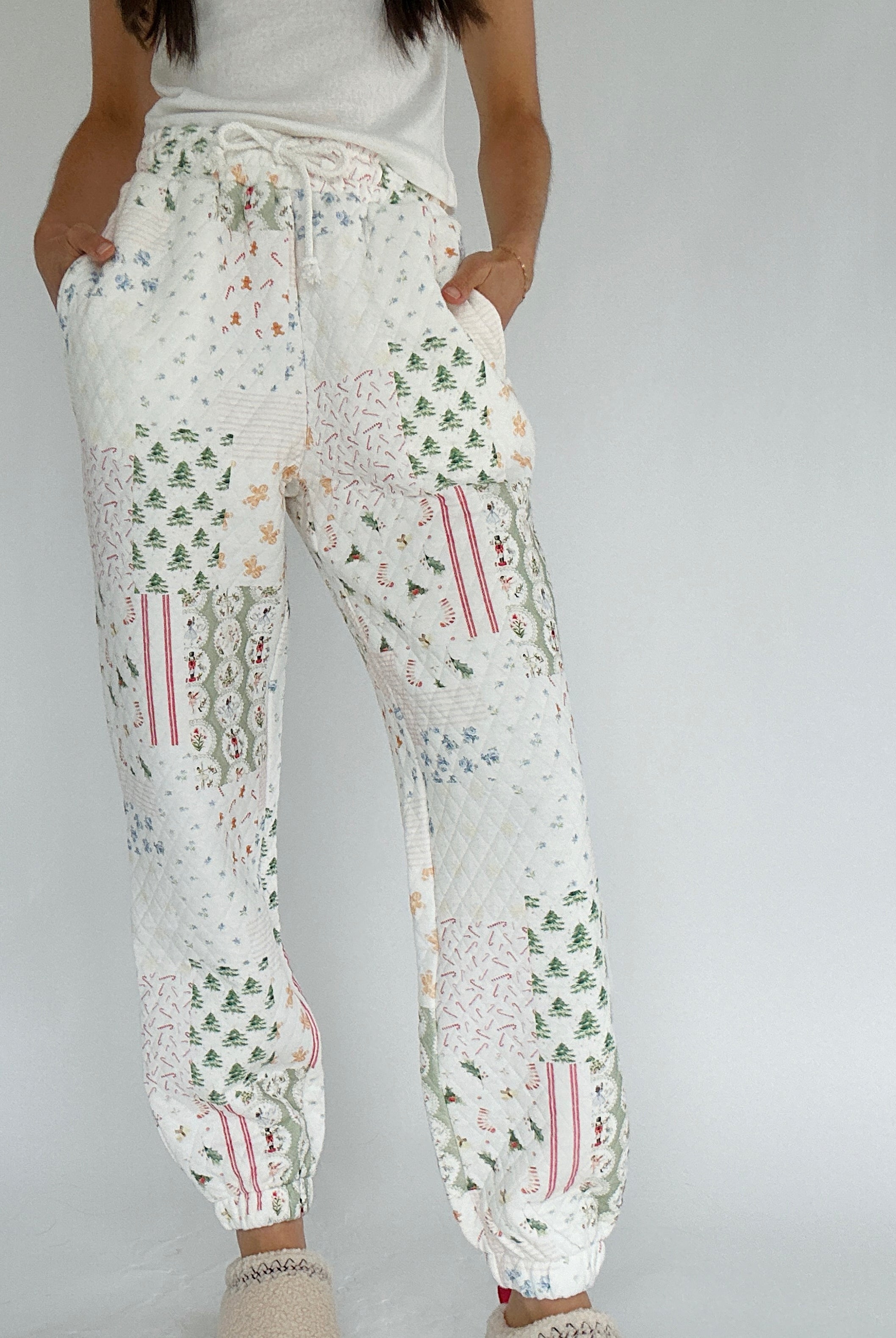 White holiday patterned quilted jogger pants worn by a person on a plain background