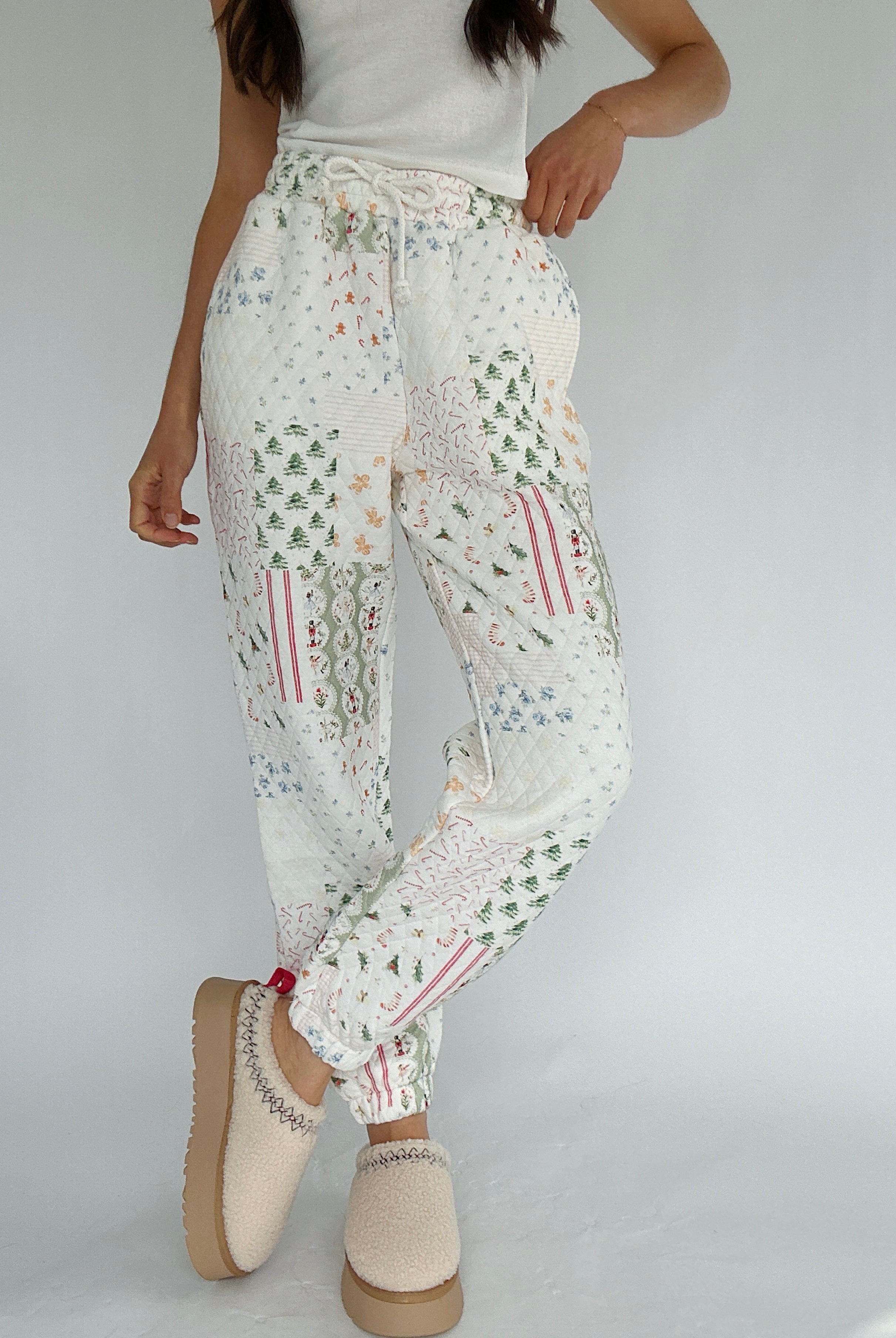 Person wearing holiday-patterned joggers pants on a plain background