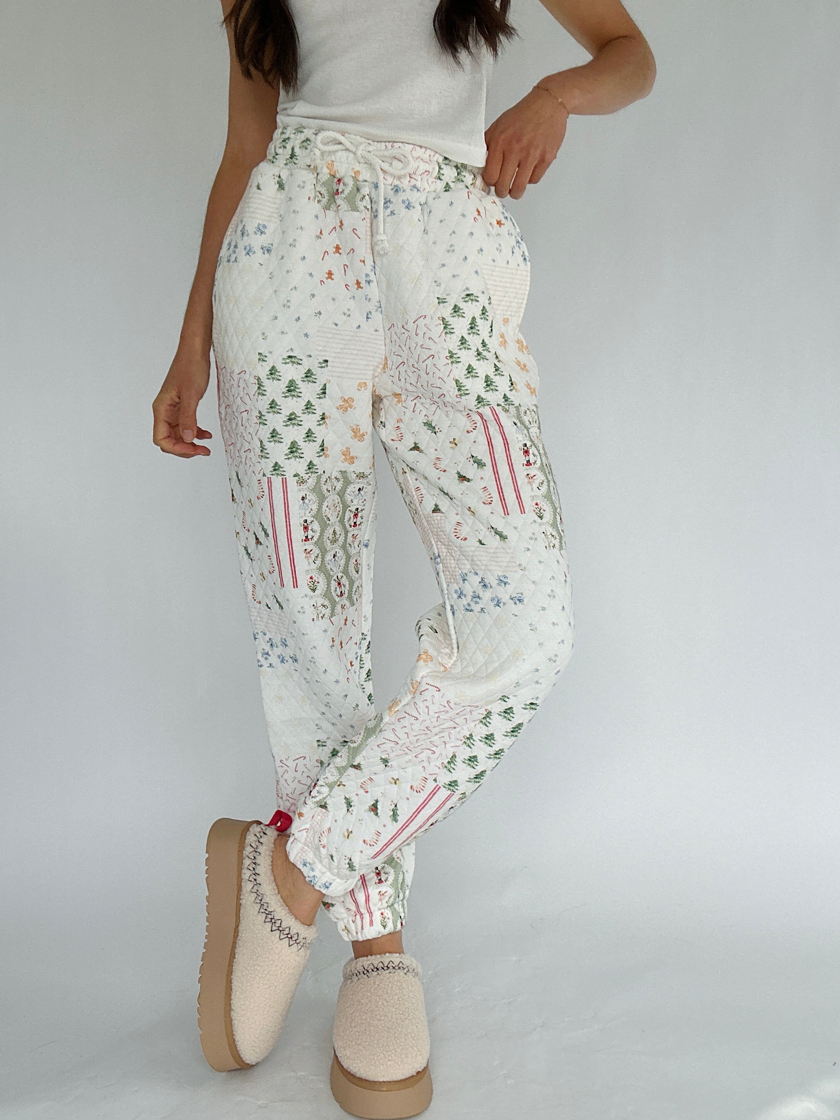 Person wearing holiday-patterned joggers pants on a plain background