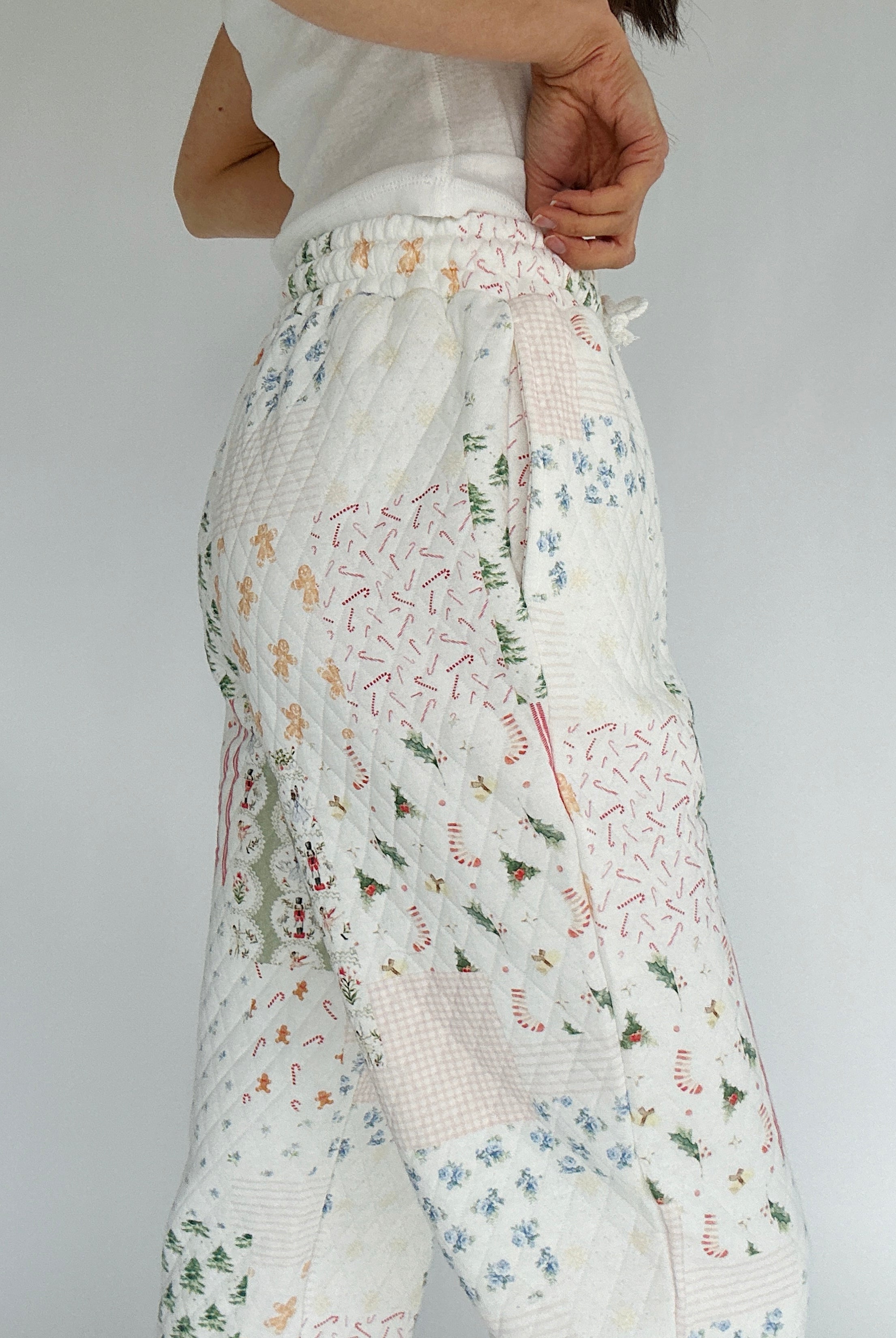 Holiday-patterned pants worn by a person on a plain background showing side pockets