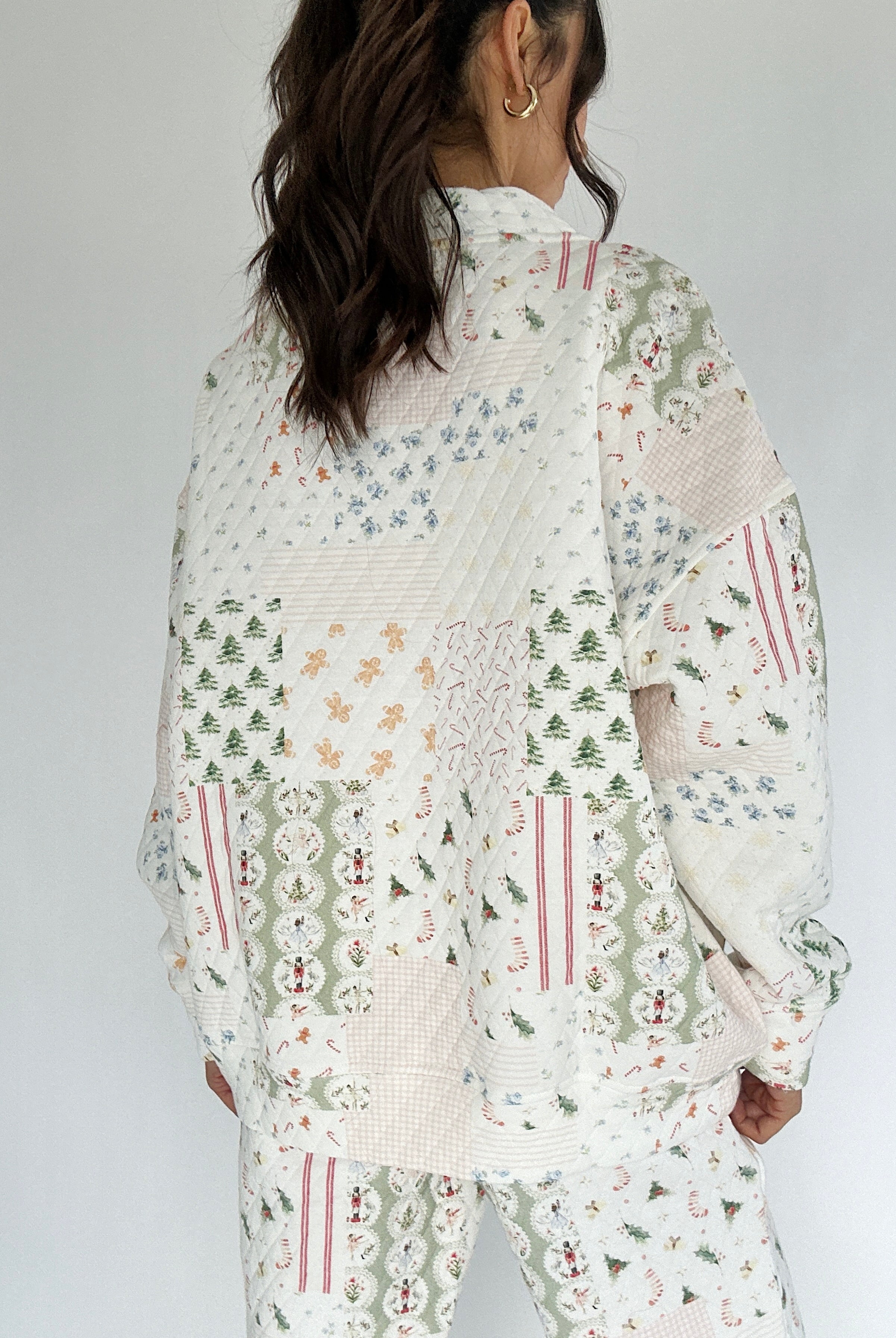 Person wearing a holiday patterned mock neck pullover with a white background from back