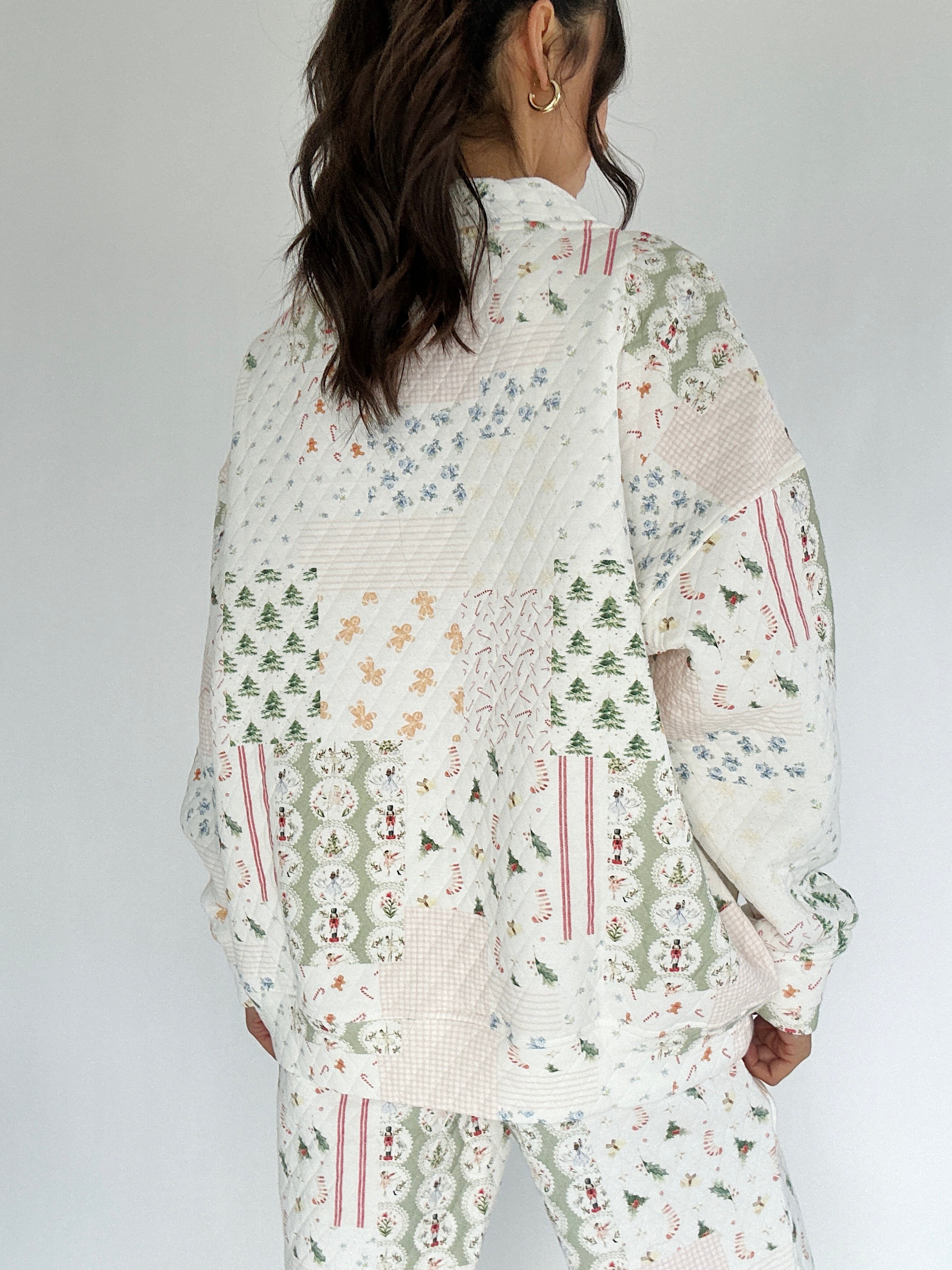 Person wearing a holiday patterned mock neck pullover with a white background from back
