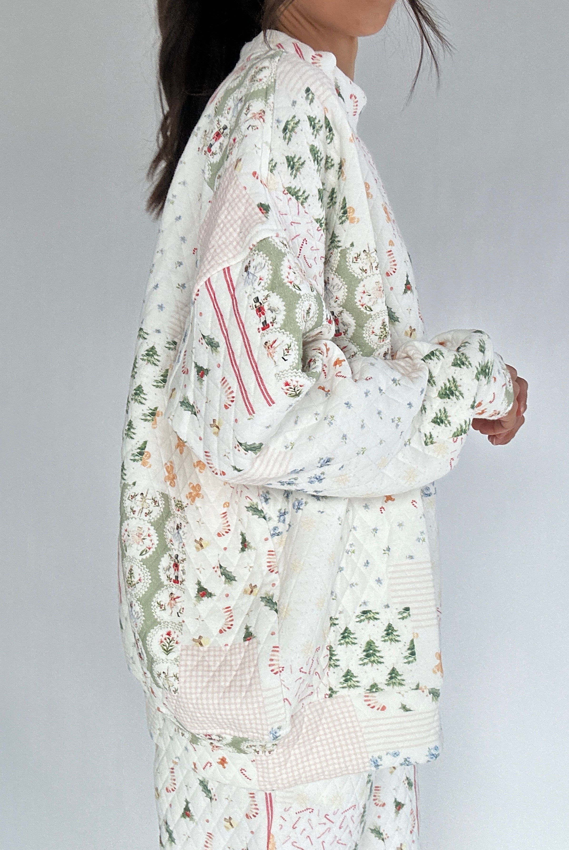 Person wearing a holiday patterned quilted mockneck with a white background from side