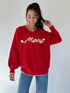 Person wearing a red sweater with 'Merry' text against a white background
