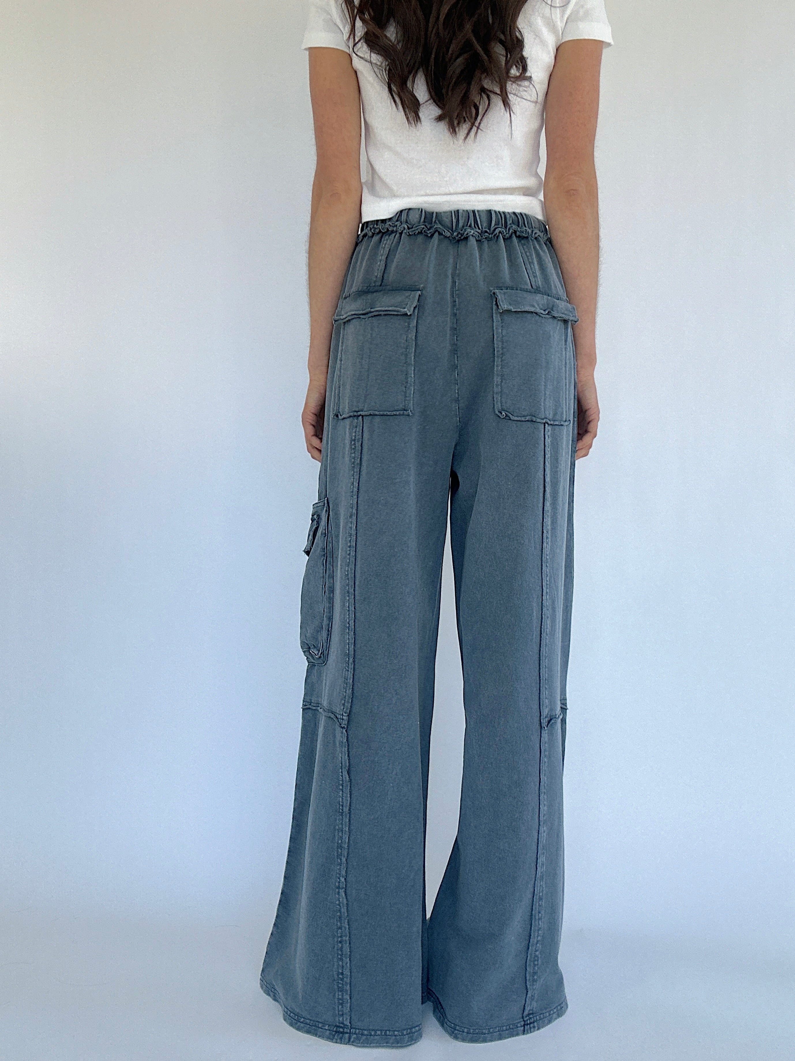 Person wearing smoke blue cargo pants with a white background from back