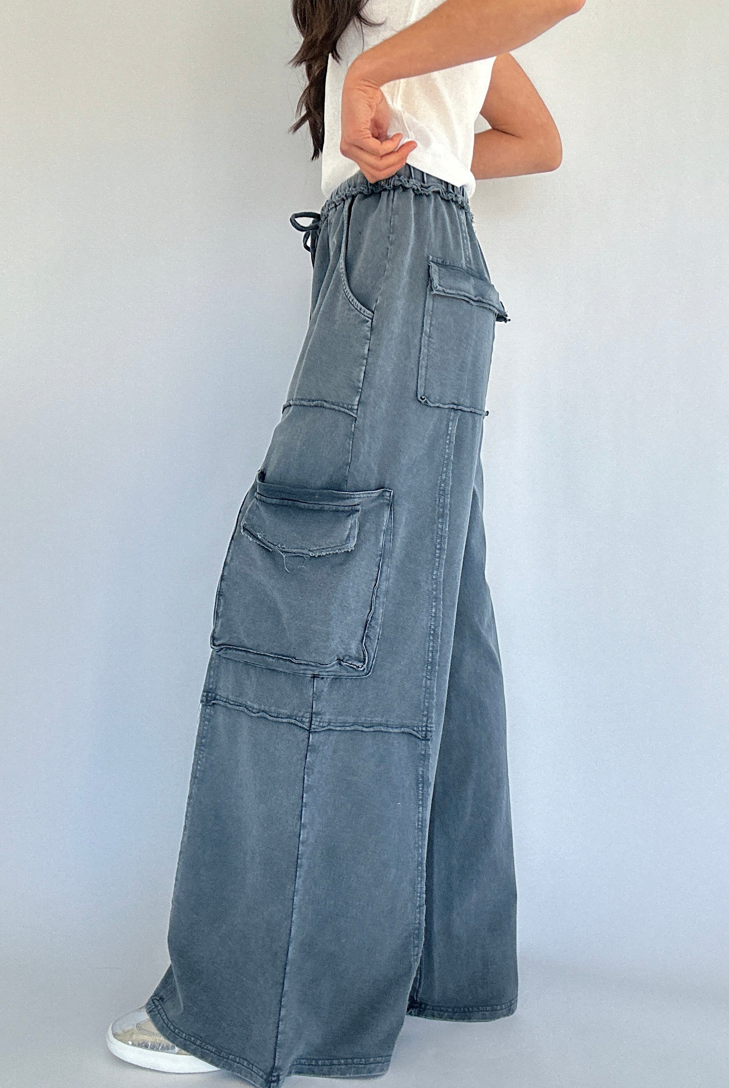 Person wearing wide-leg cargo sweatpants with multiple pockets on a plain background