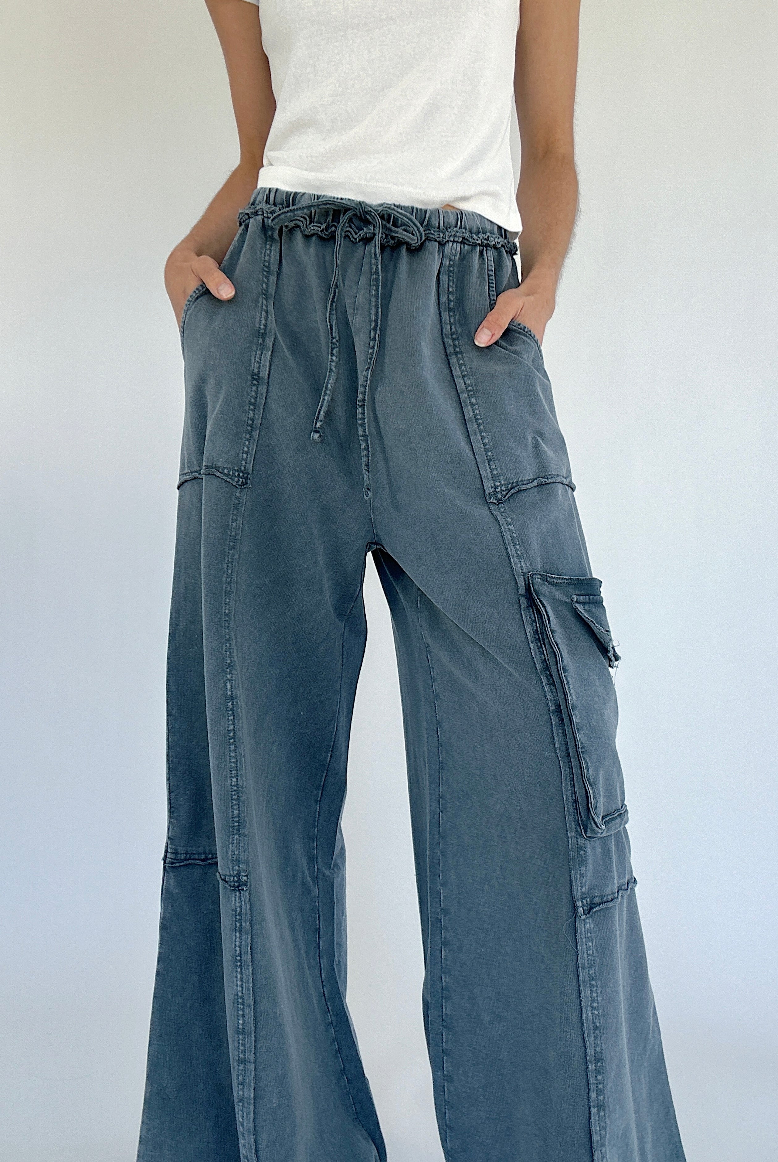 Person wearing smoke blue cargo pants with a white background showing elastic drawstring waist