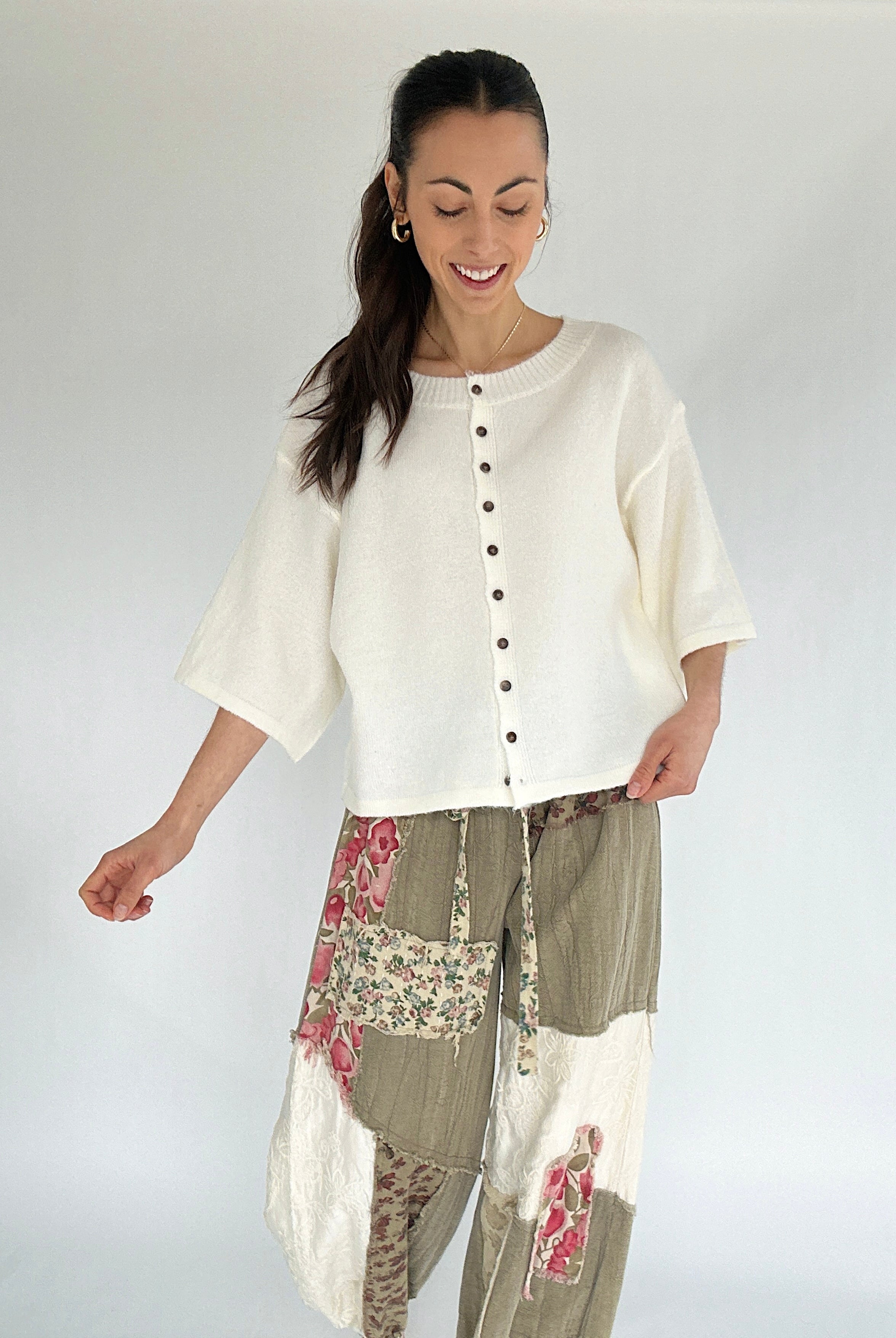 Woman wearing a white top and patterned pants on a plain background