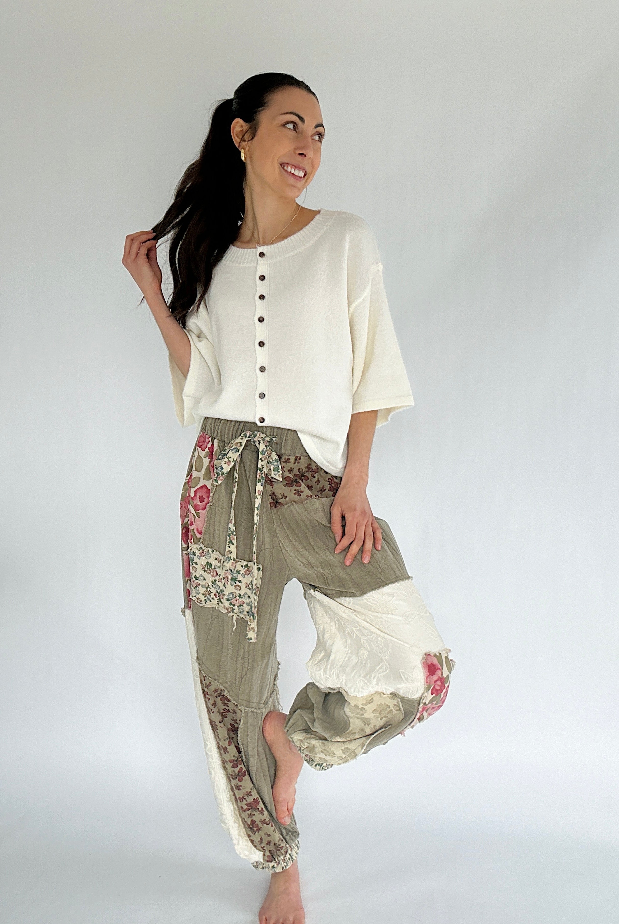Woman wearing a white top and patterned pants on a plain background