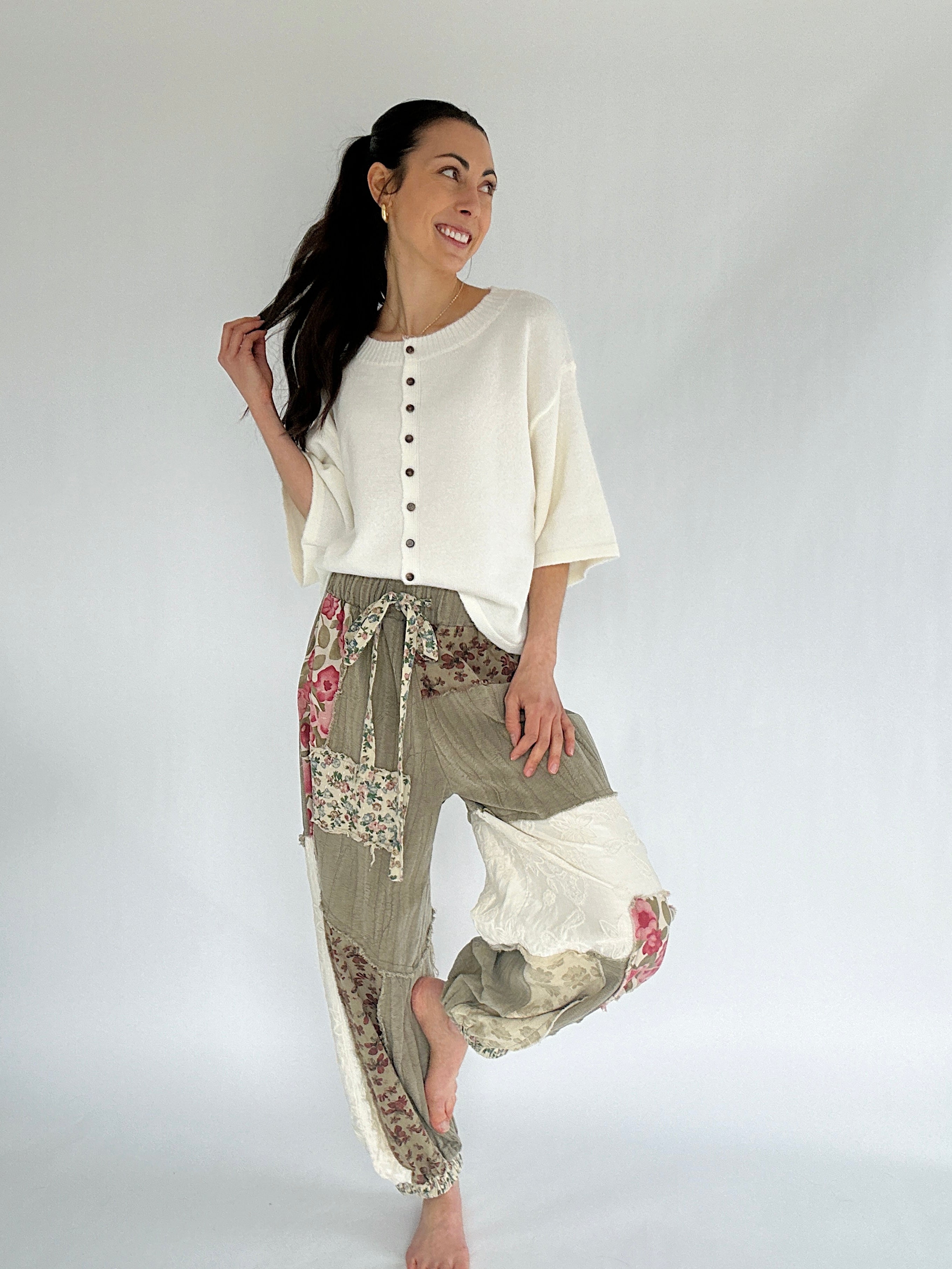 Woman wearing a white top and patterned pants on a plain background