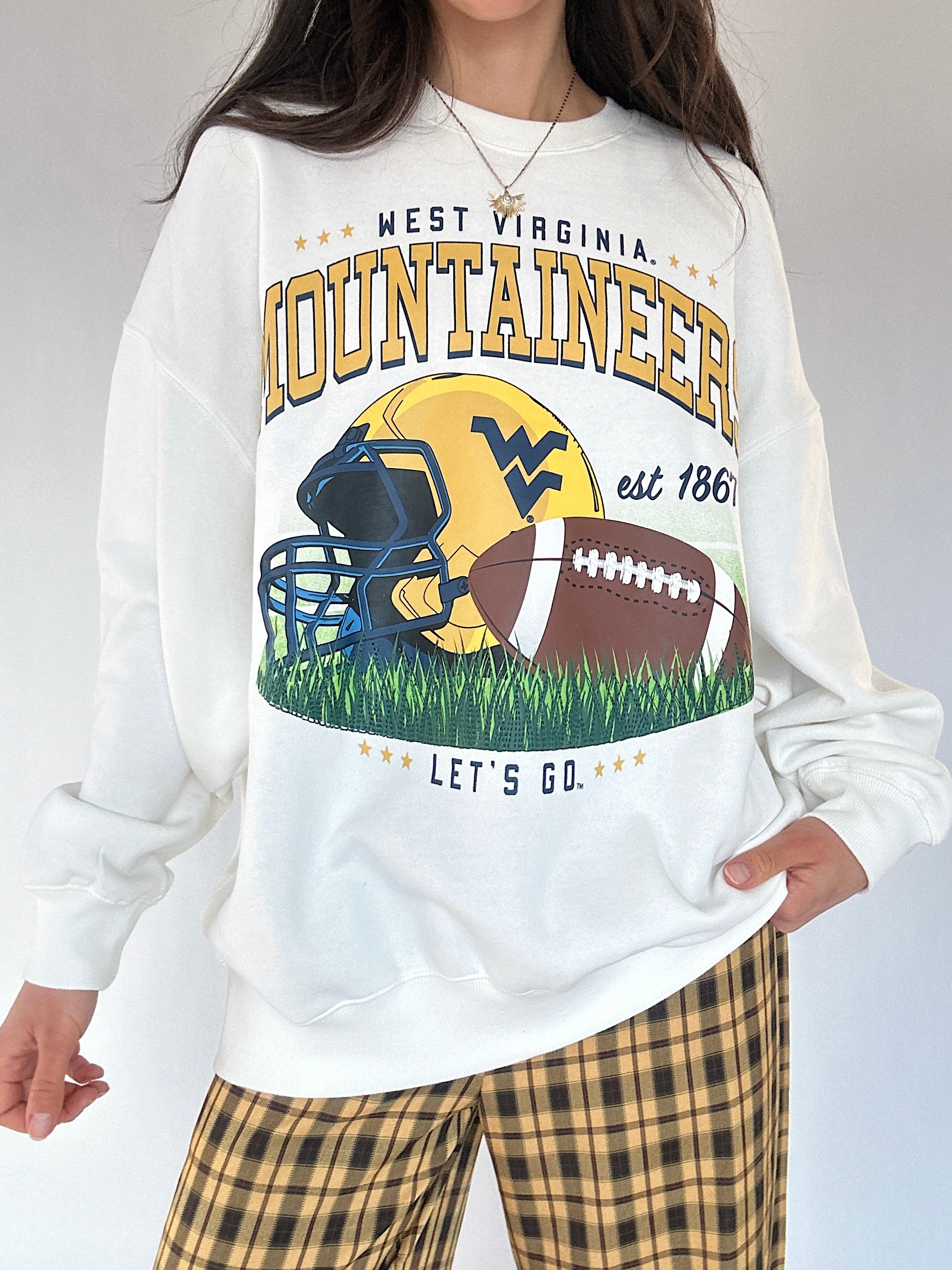 Person wearing a white sweatshirt with West Virginia Mountaineers football graphics and text.