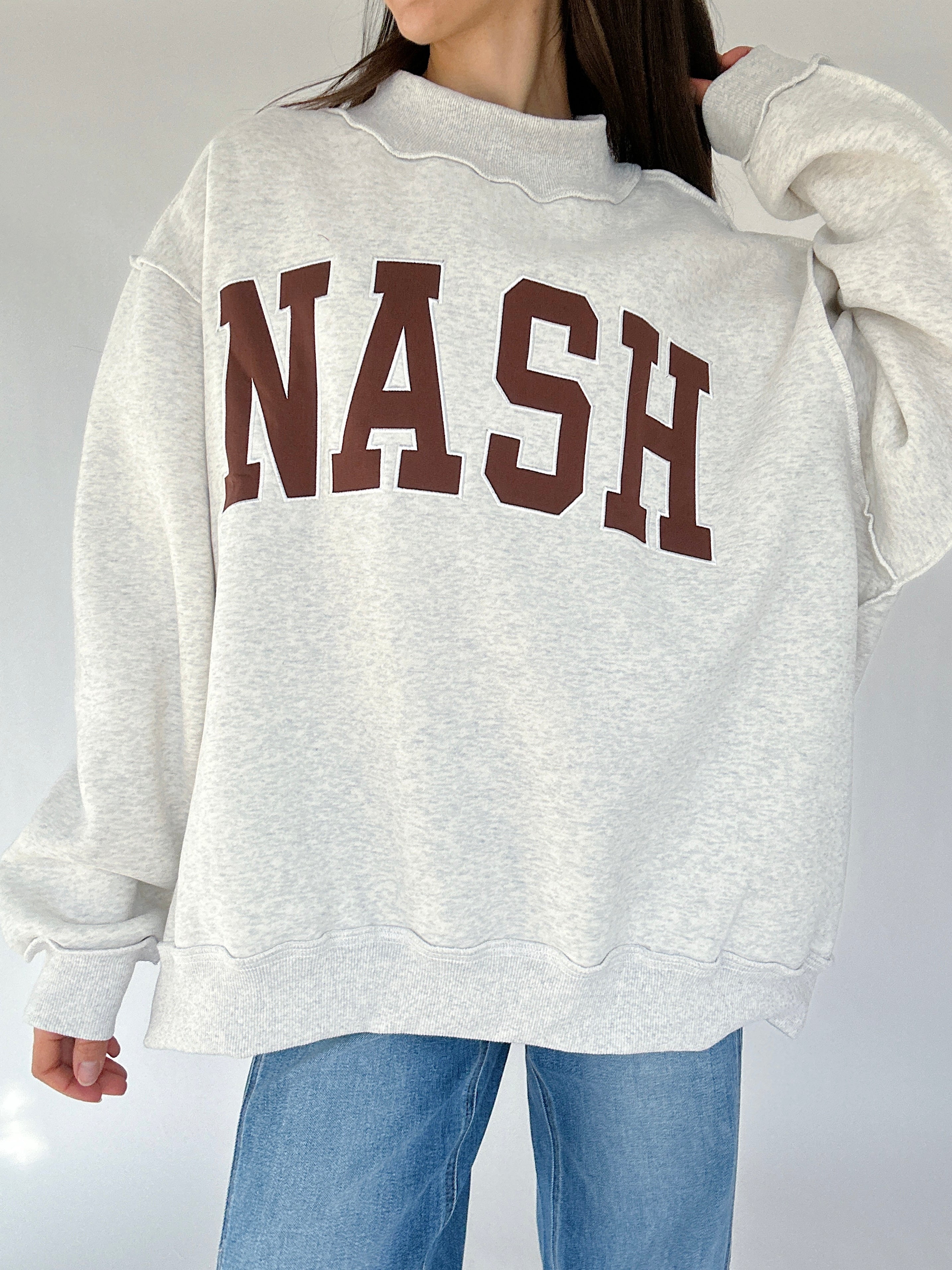 Gray mockneck sweatshirt with 'NASH' printed in brown on a plain background