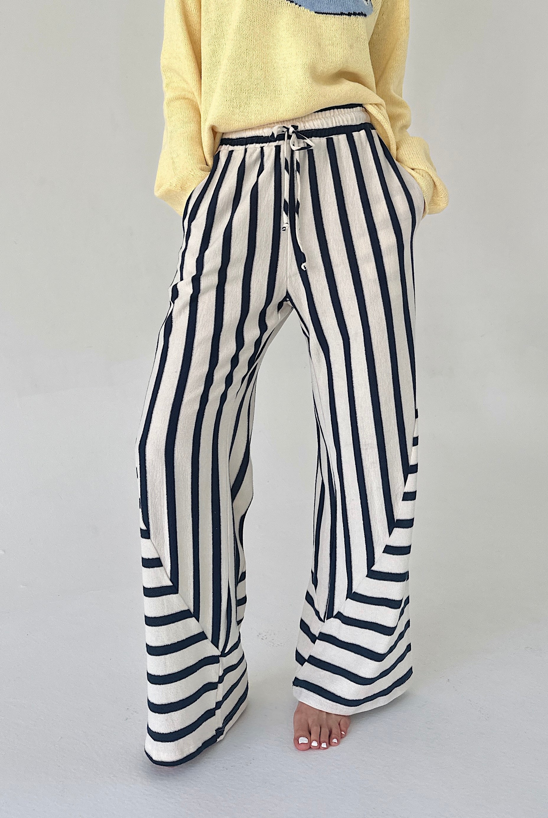 Person wearing navy and white striped pants on a plain background