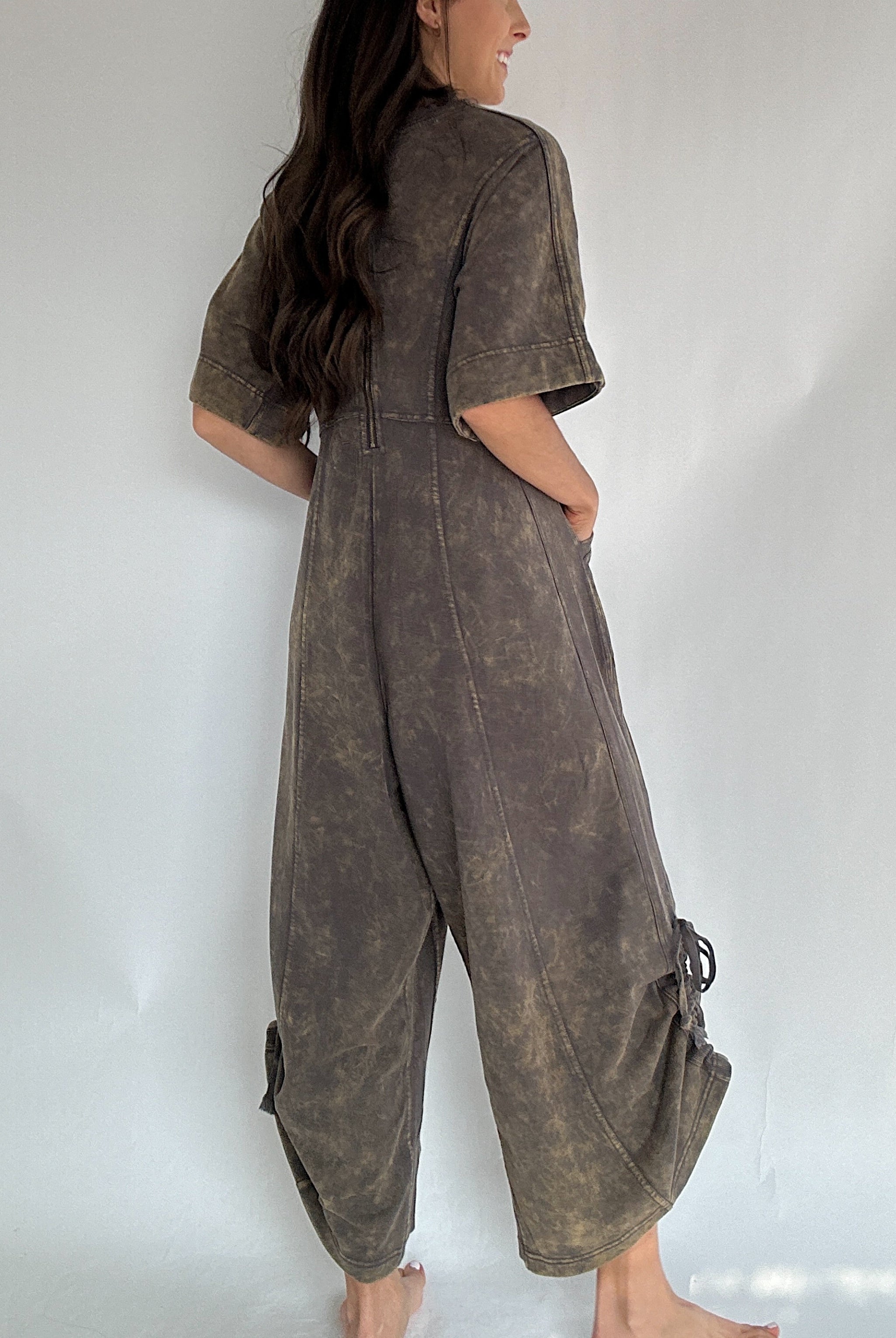 Person wearing a brown terry knit jumpsuit against a white background to show back view