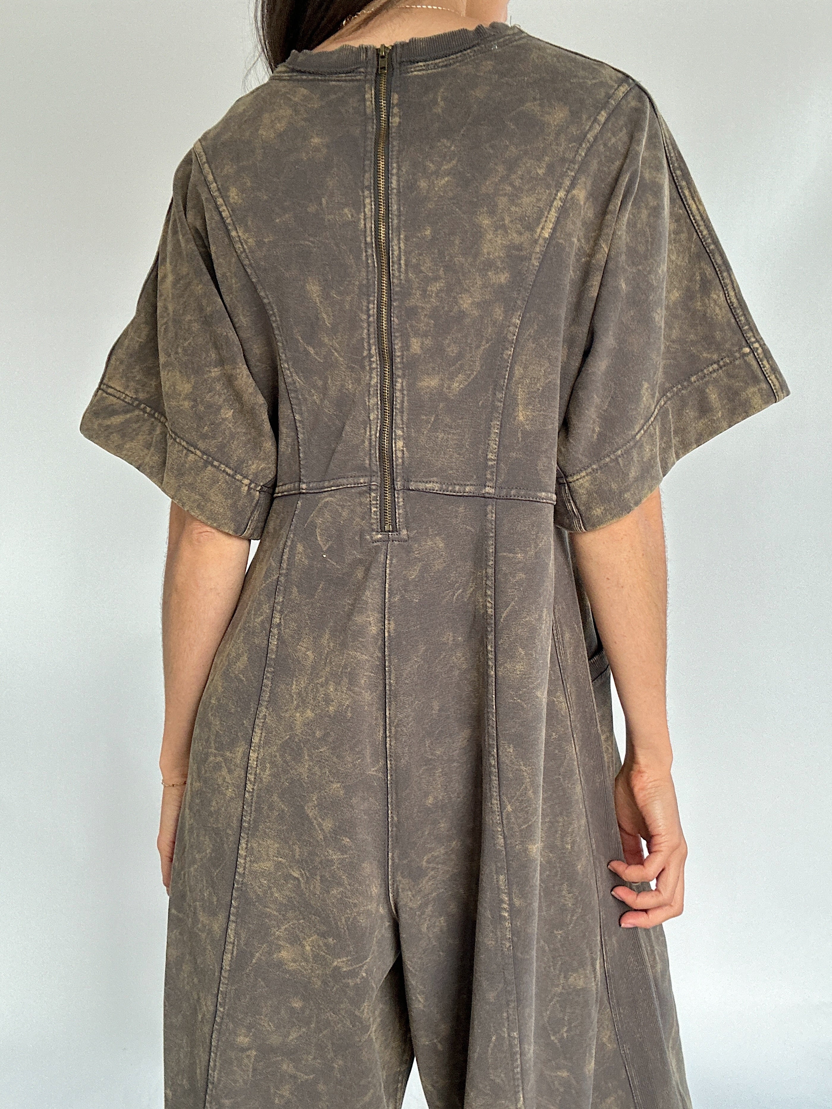 Brown distressed jumpsuit on a plain background showing the back zip detail