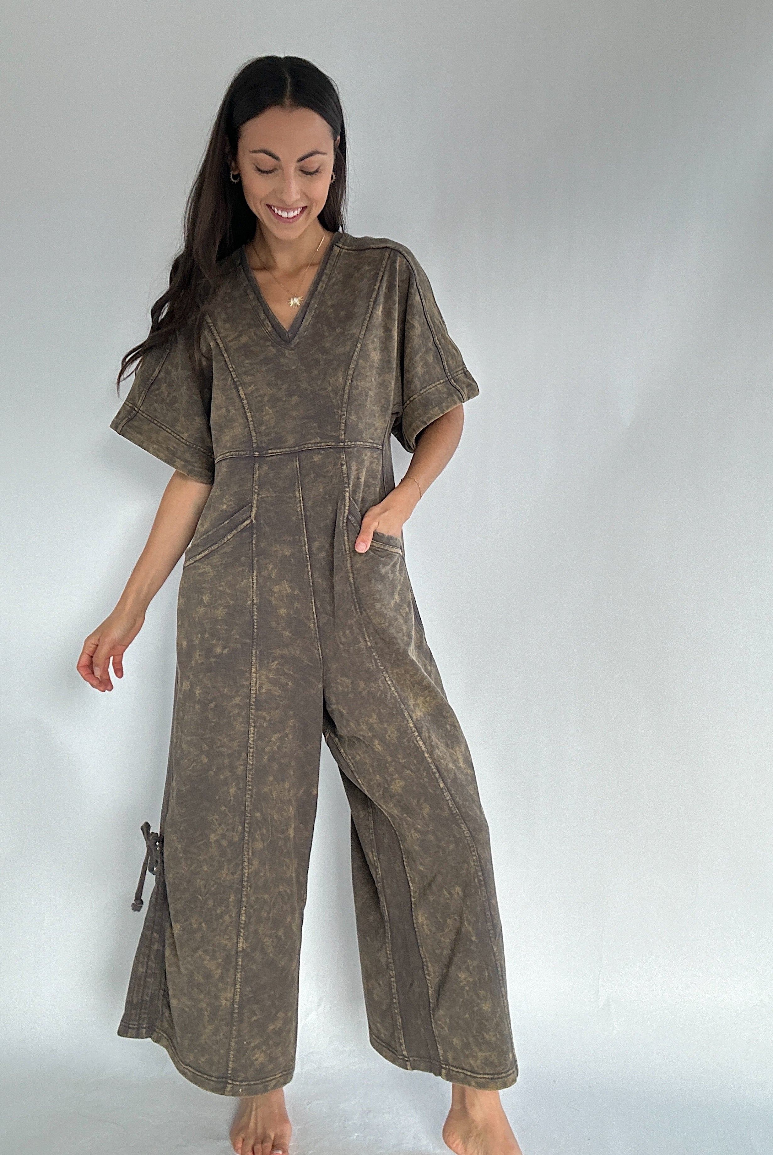 Woman wearing a brown jumpsuit on a plain background