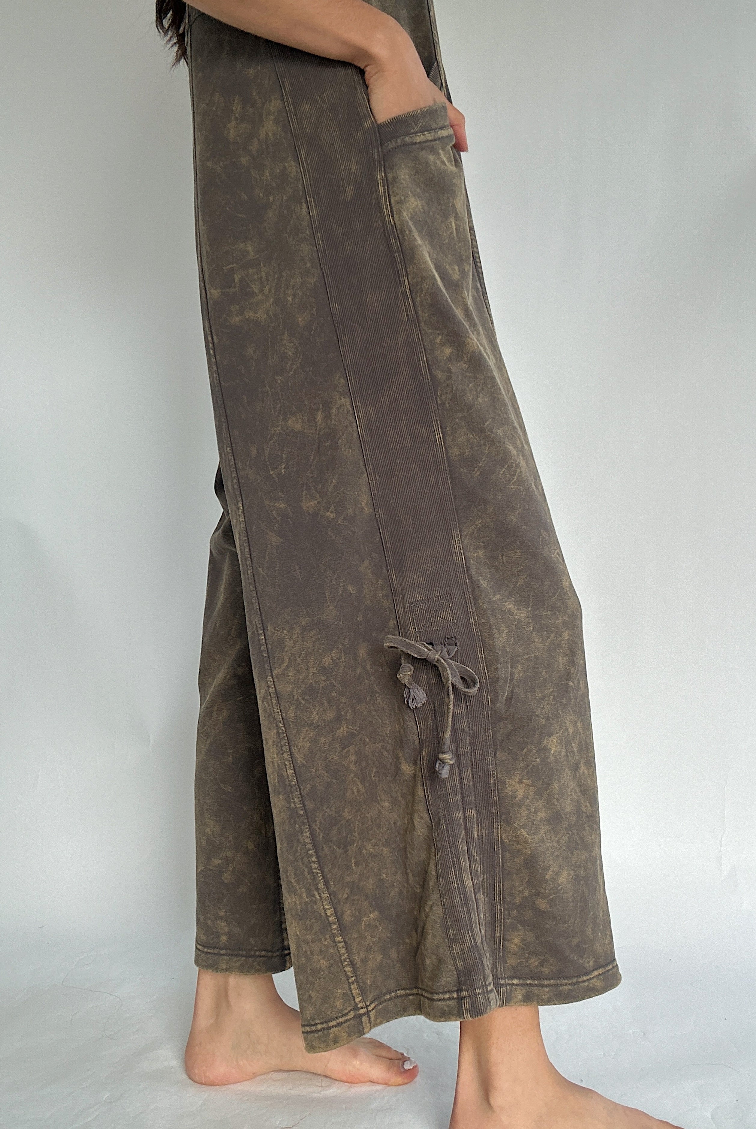 Brown wide-leg jumpsuit worn by a person on a plain background to show the cinchable tie accent