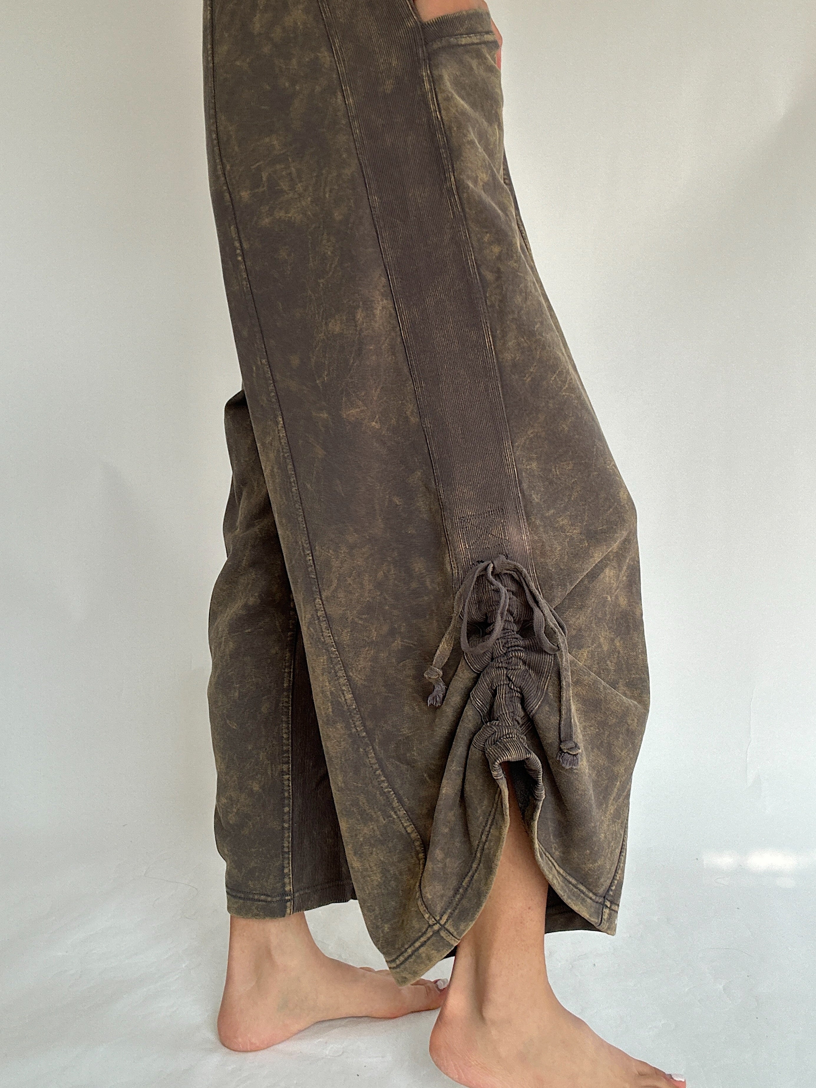 Brown mineral washed jumpsuit on a white background showing the up close detail of the side tie on bottom hem