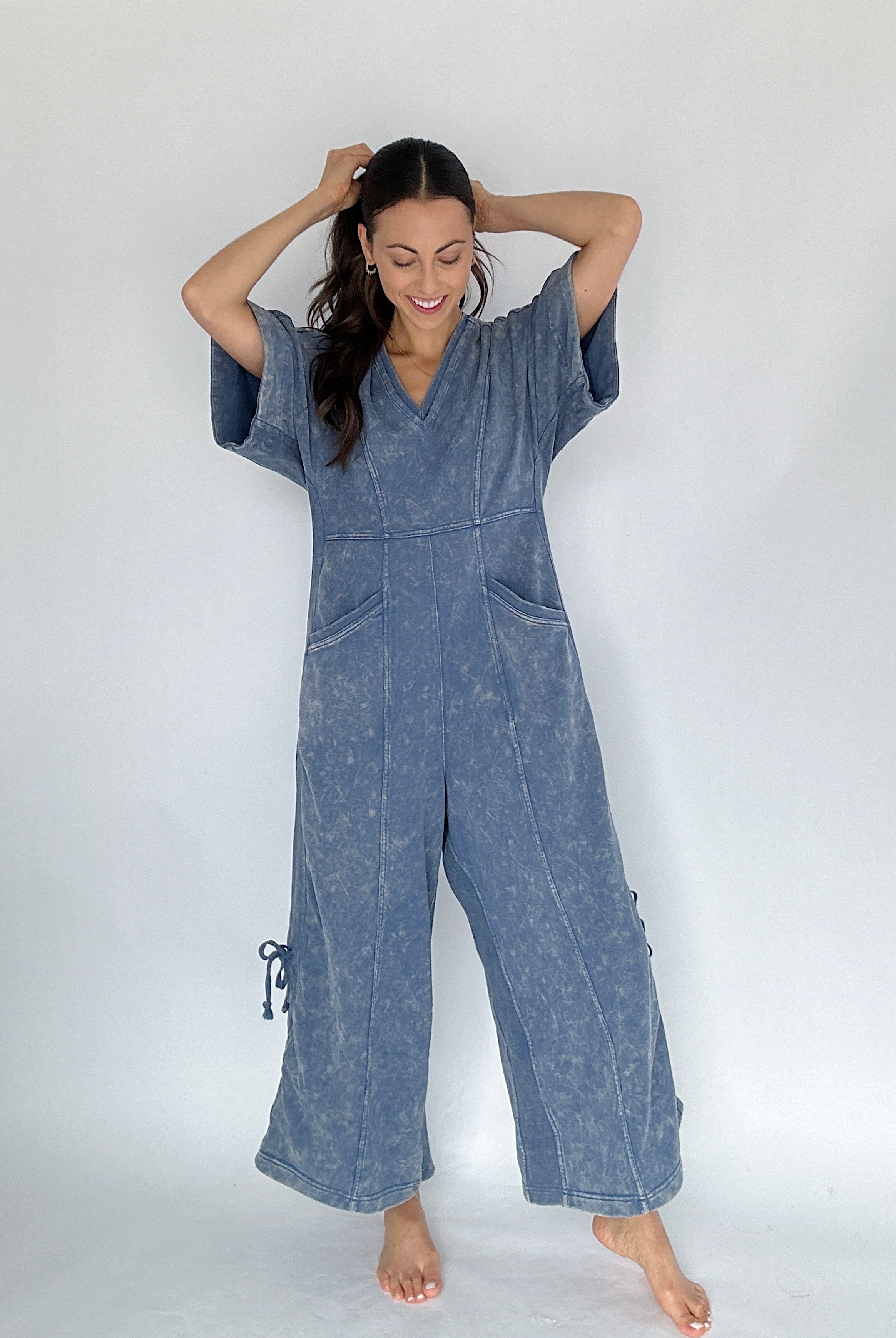 Woman wearing a blue jumpsuit against a white background from the front