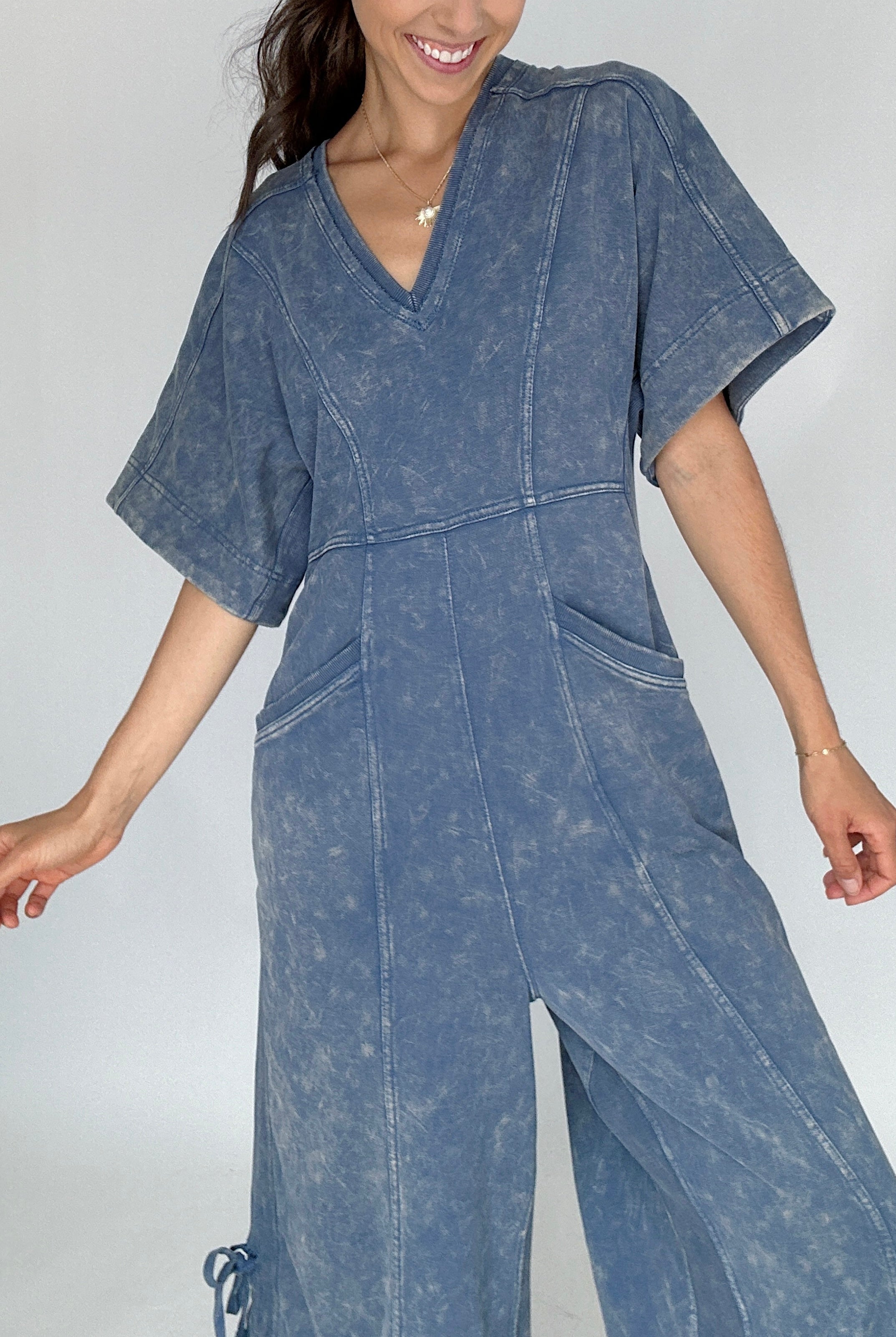 Woman wearing a blue denim jumpsuit against a plain background close up of top