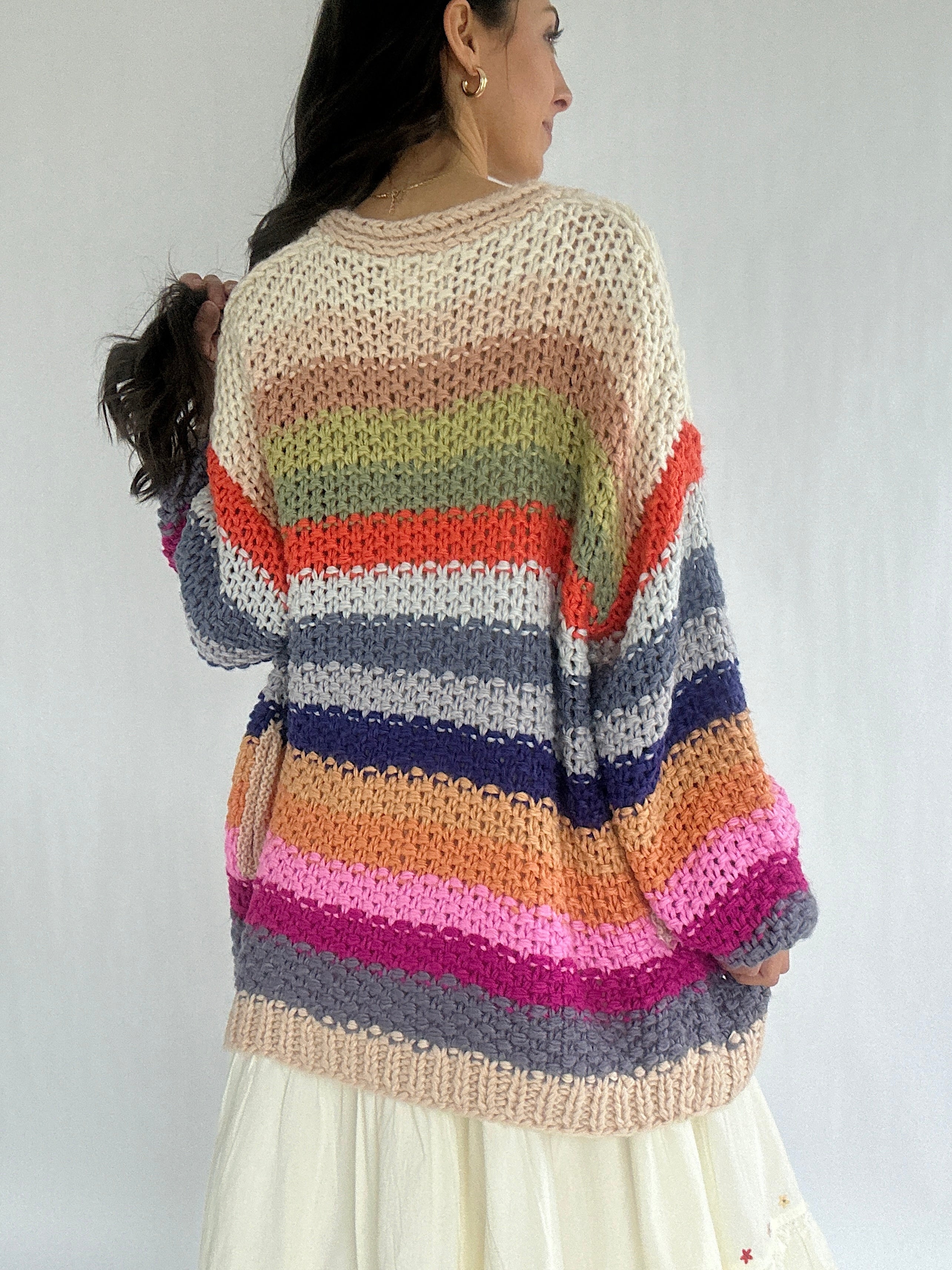 Person wearing a colorful striped sweater against a plain background showing back